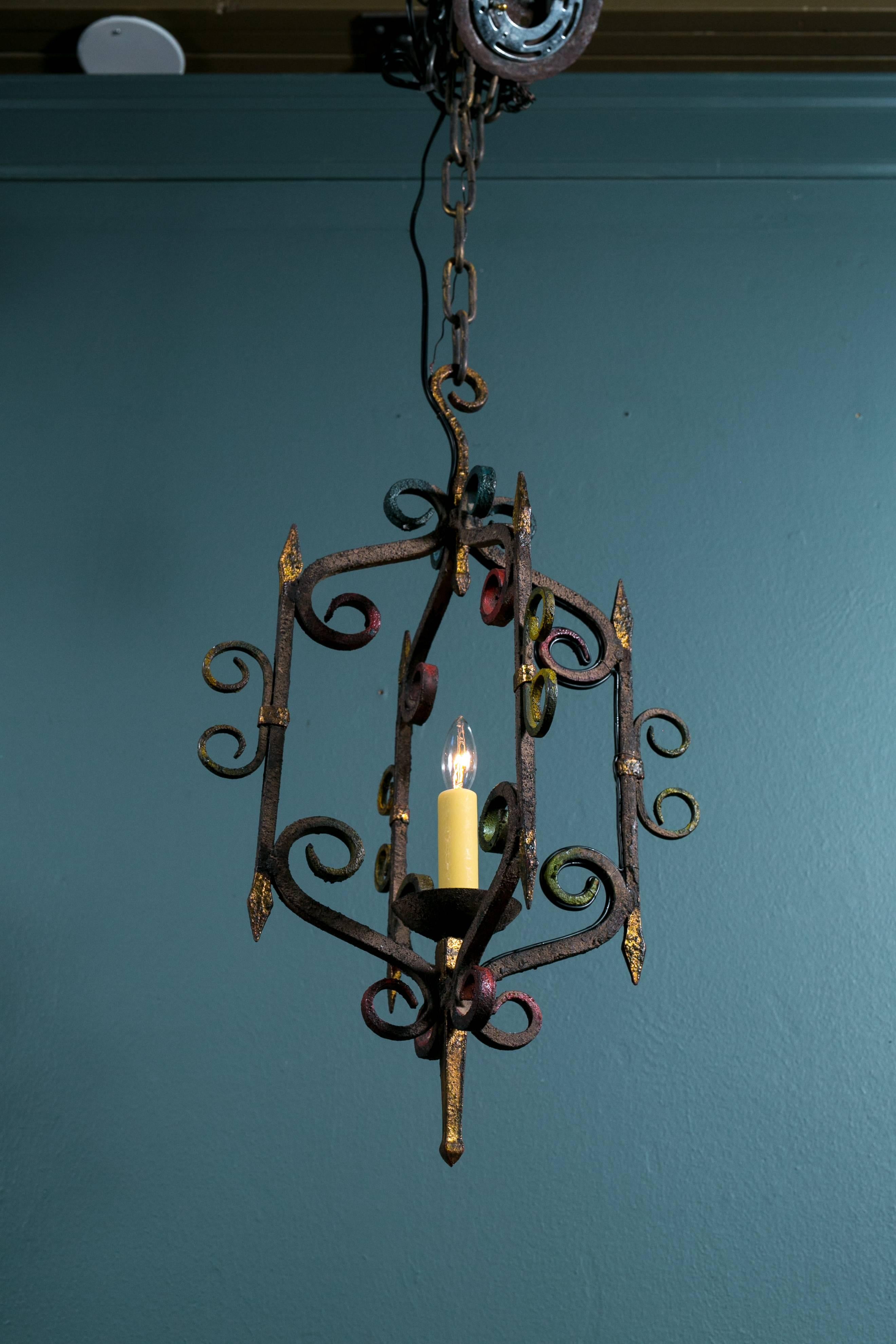 Hand-forged iron light, newly rewired for use in the USA with all UL approved parts and a single candelabra socket. Wonderful crusty texture on the iron with subtle colors painted on the scrolls and gilt accents. Colors are much less noticeable in