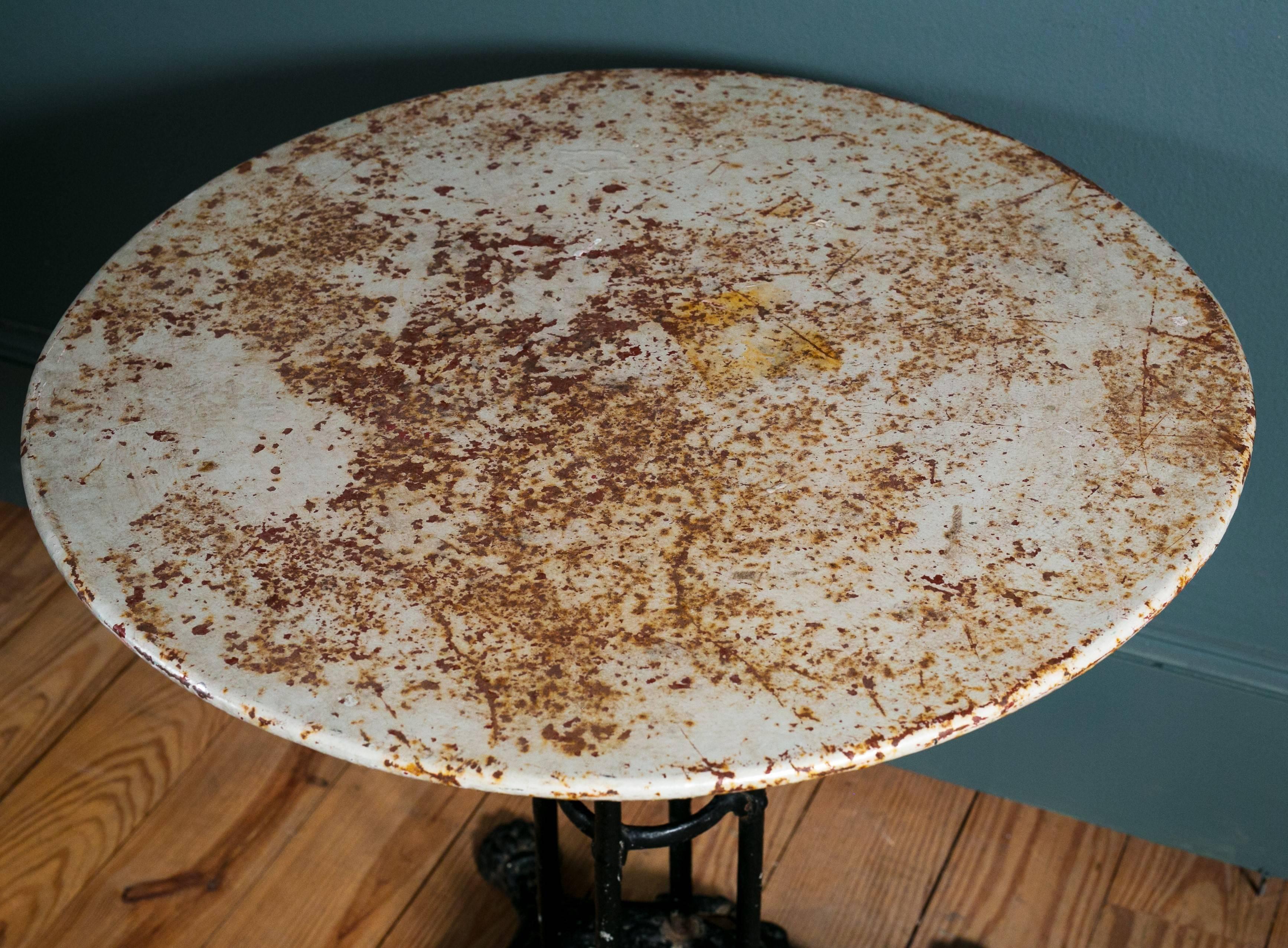 Antique claw-foot, iron base bistro table with antique painted metal top. Very pretty casting on the base with original paint. From France, circa 1890s. Larger than usual in size, see dimensions.