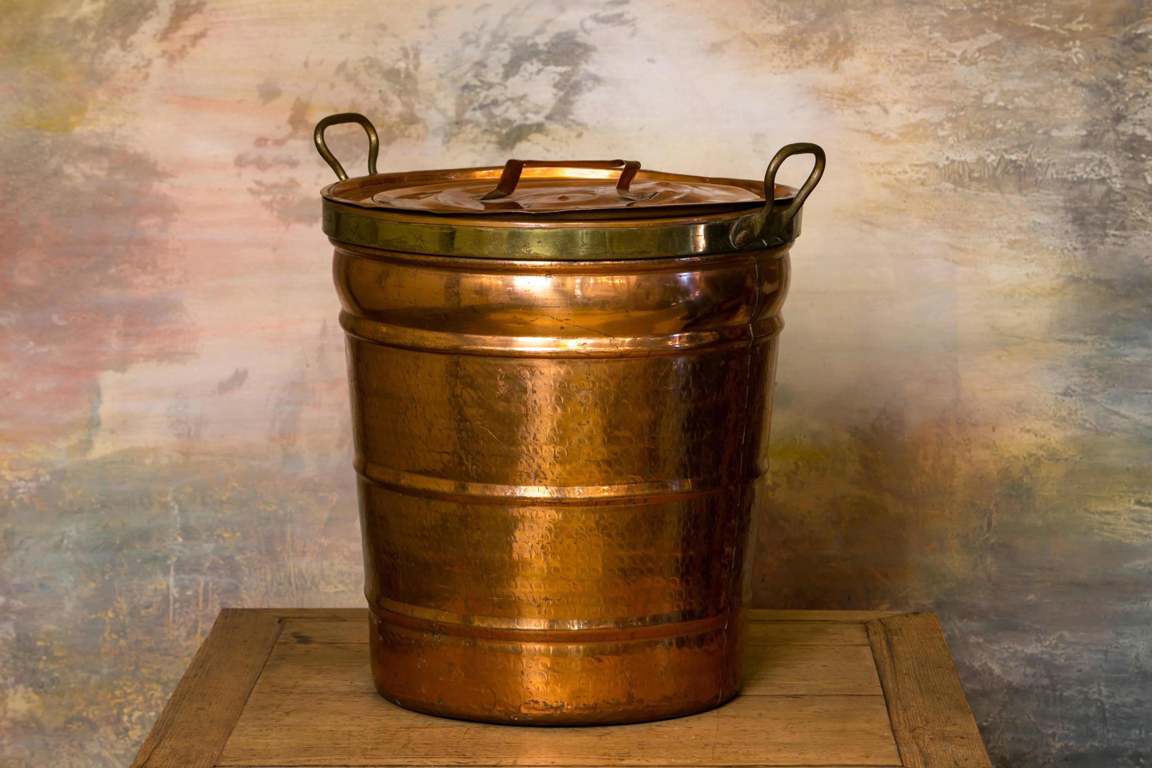 Hand-hammered copper pail with two handles on the top and a lid with handle.
Brass banding around the top and on the handles. Would make a great wastepaper basket.
              