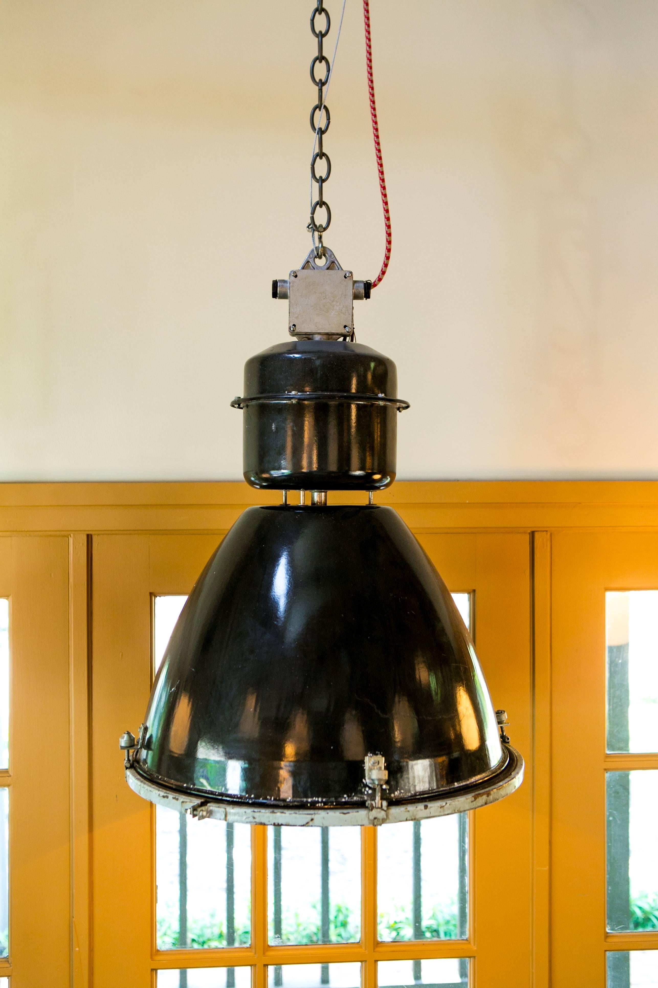 Vintage black enamel Industrial factory light with white interior and a clear glass diffuser. Newly wired with all UL listed parts and a single porcelain Edison socket. Hangs from a silver metal cable and red hounds-tooth fabric wrapped cord. Comes