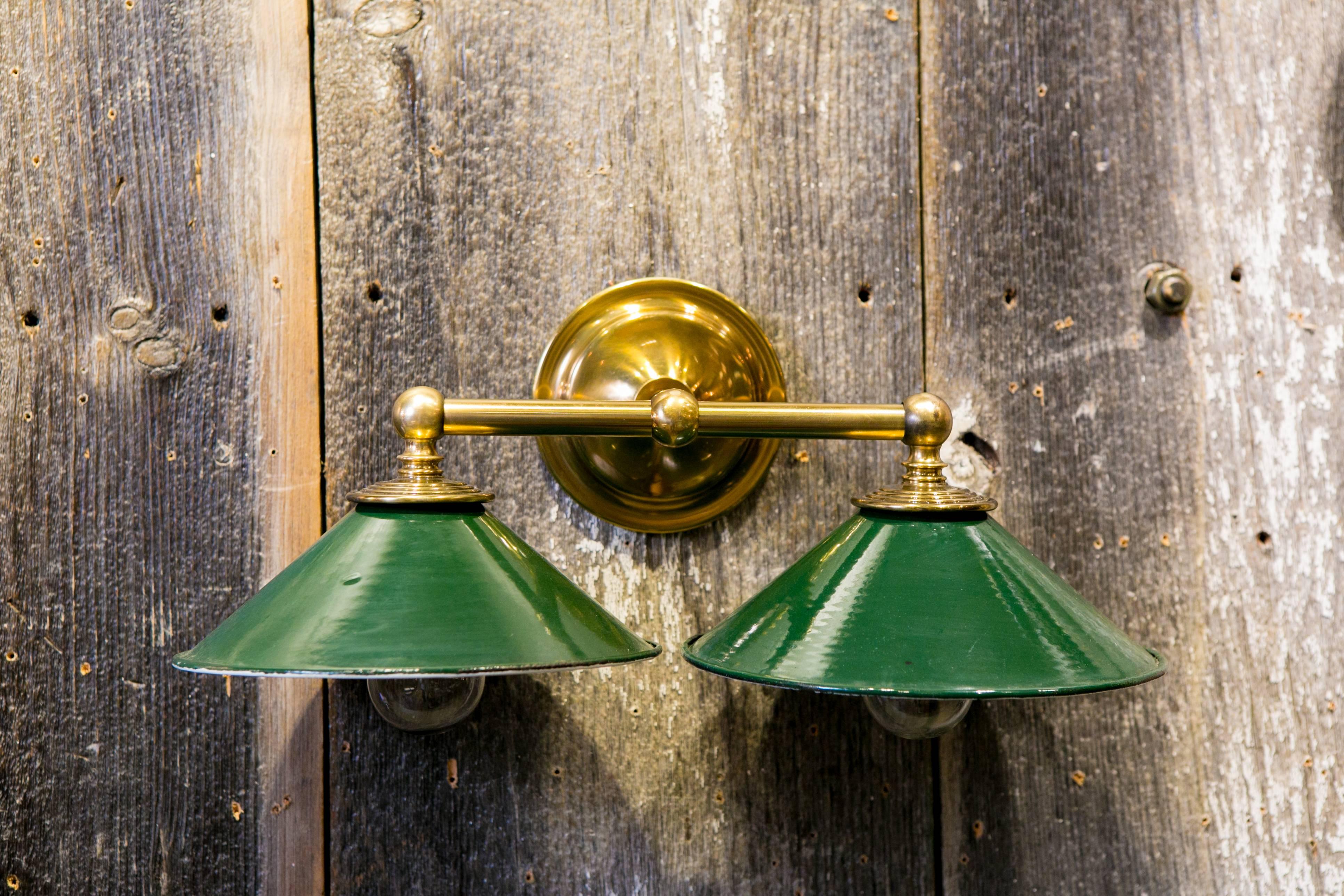 Vintage green enamel shades from Belgium, circa 1920 with white interiors.
Our Exclusive Design pairing vintage shades with a new brass two-light sconce, newly wired with all UL listed parts. Five available, price is for one sconce. Great for over a