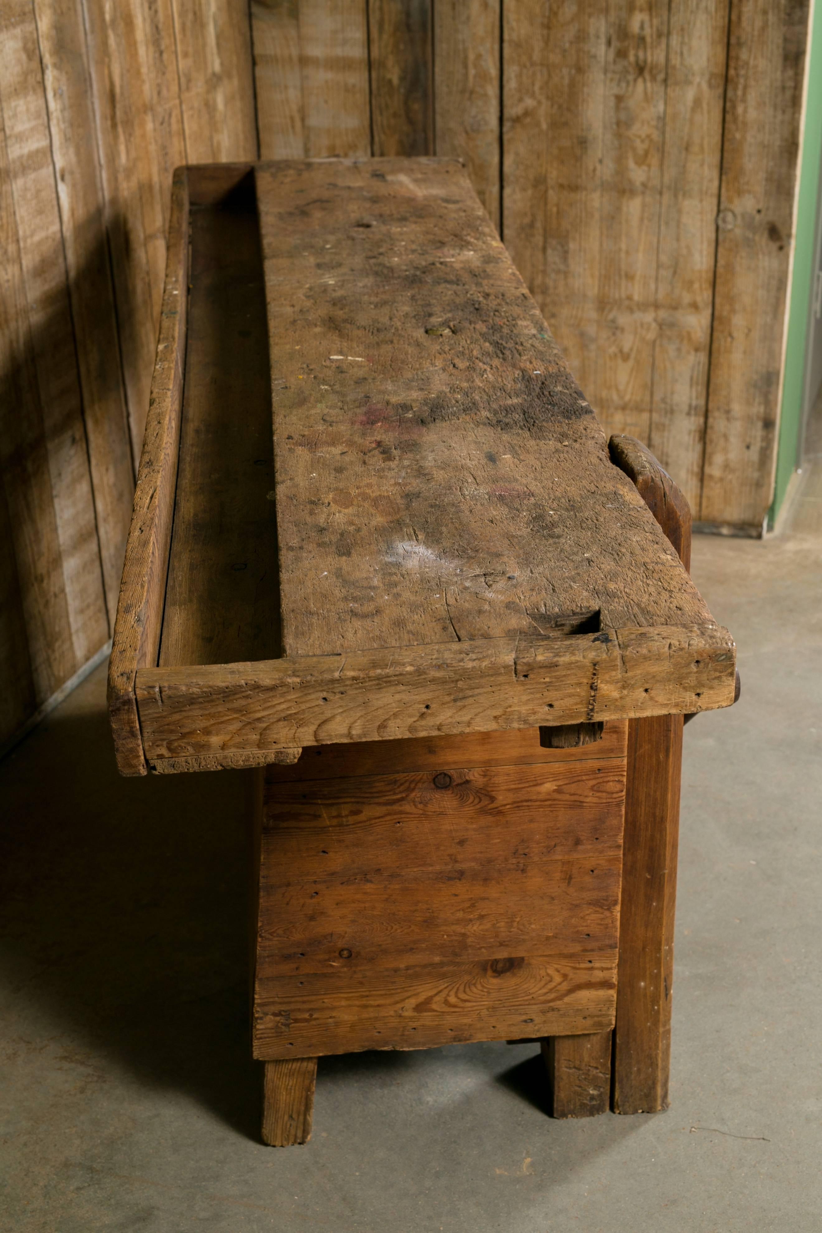 Unusual French work bench with closed front and shelf below. Features a trough top and original iron vise on the front. Would make a great rustic kitchen island, console or sofa table.