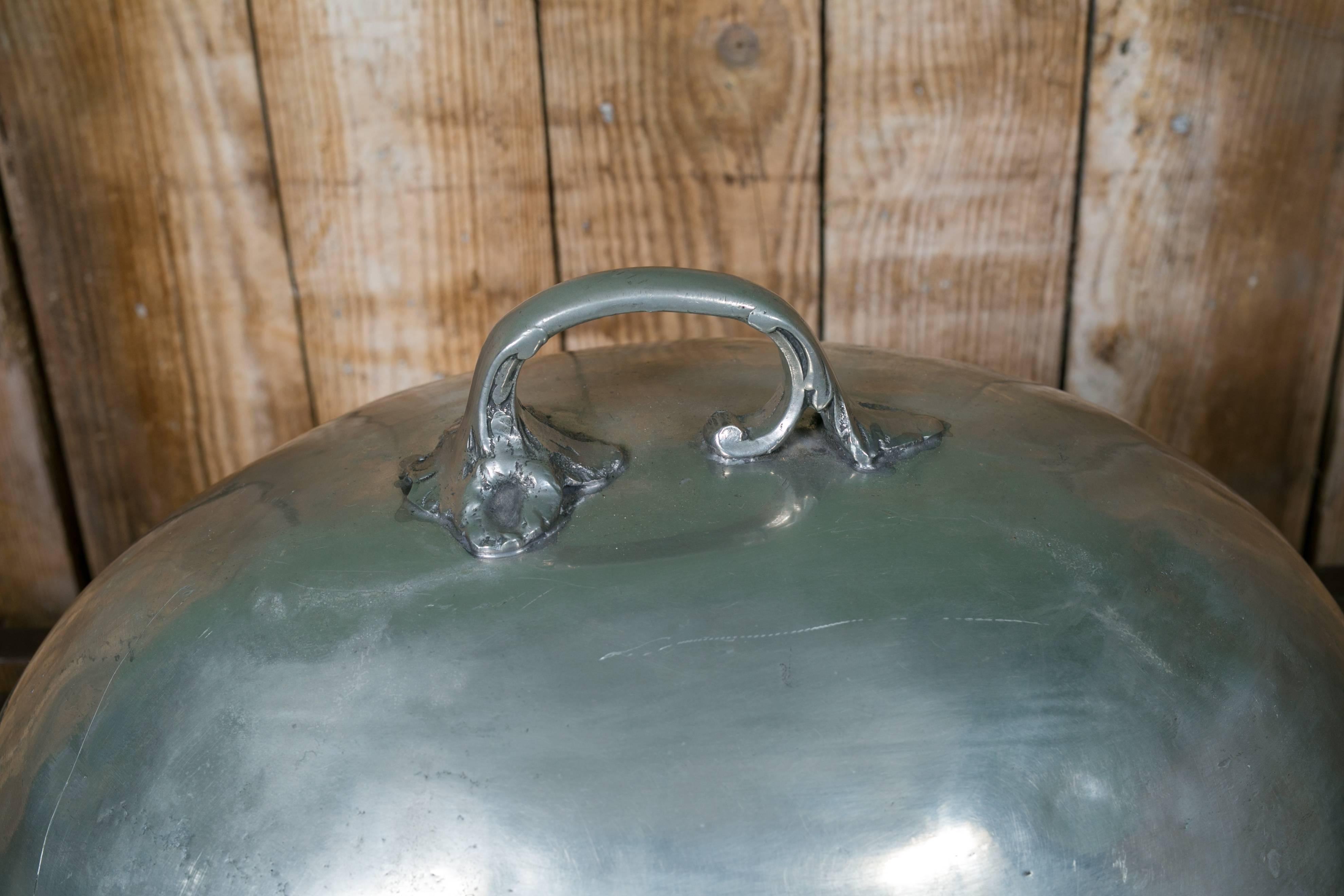 Very heavy, simple, large silver-colored cloche from Rita Jorden in Belgium. Hand-cast construction with a beautiful handle on the top. Decorative and functional. This is a a piece that will become a keepsake.  Please notice a few dents in the