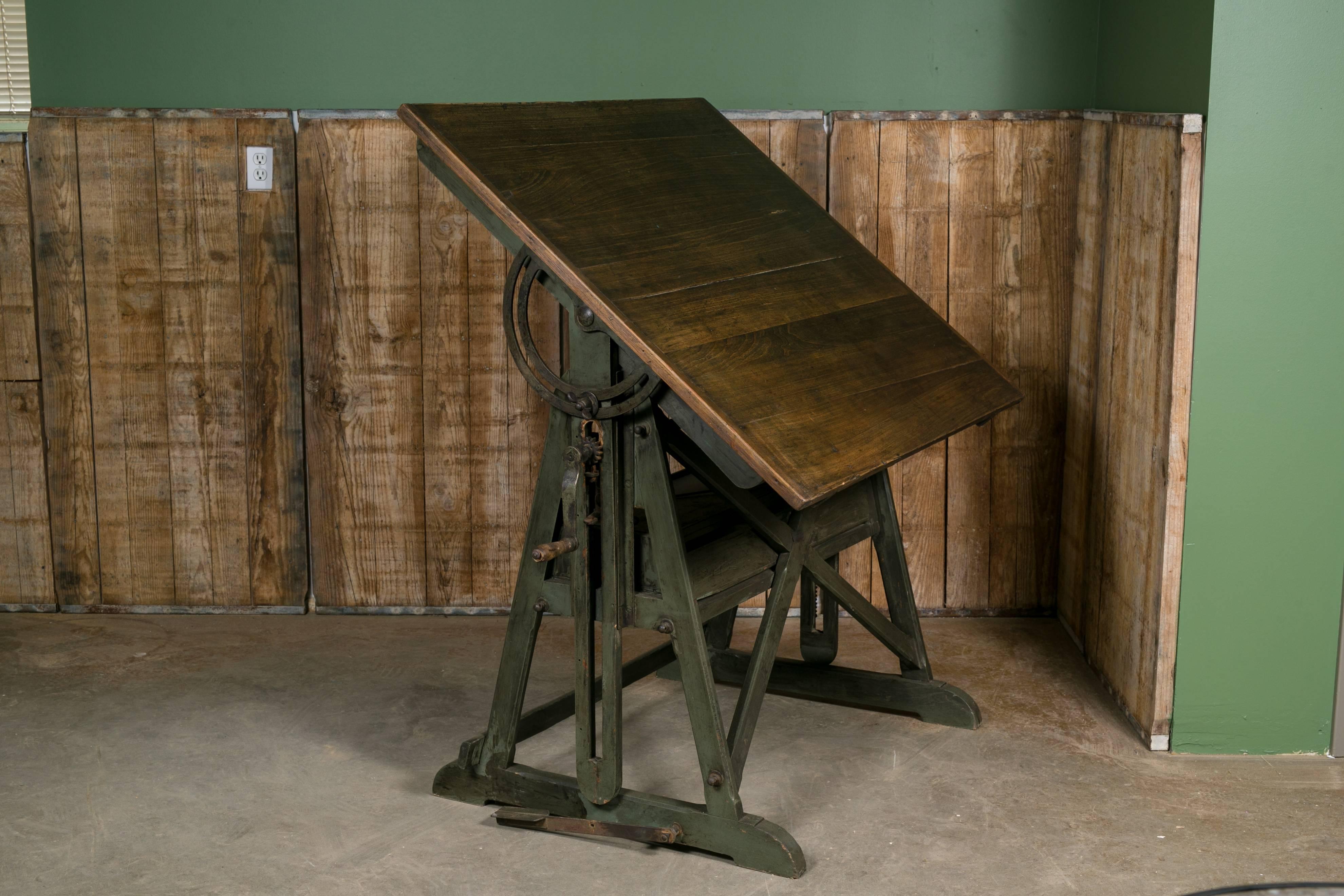 Beautiful Industrial drafting desk with dark wood top and green base from Belgium, circa 1900. Original wood top and green painted wood and iron base. Features a long drawer in the middle of the fixture for storage. Top tilts forward or can be
