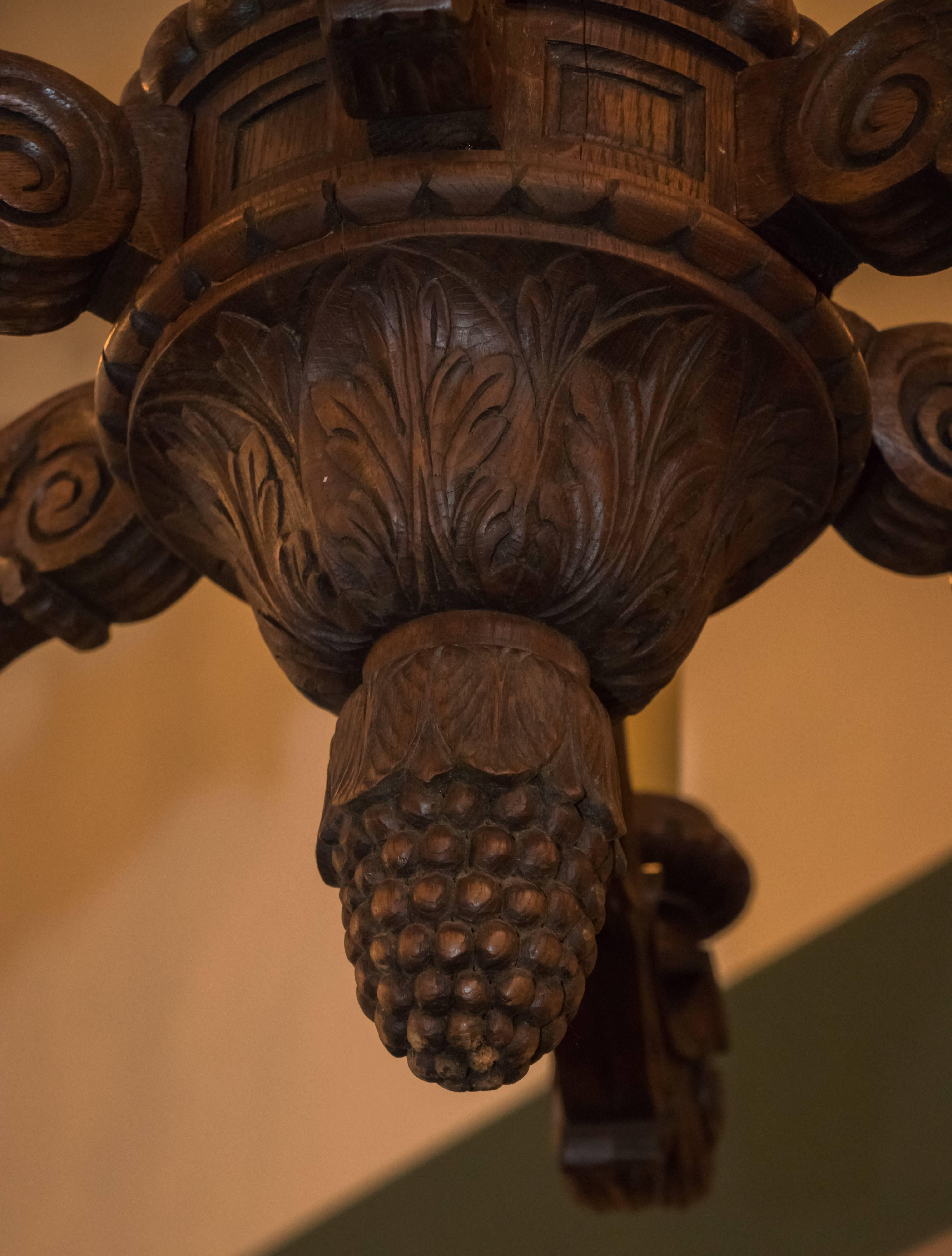 Large and heavy solid carved oakwood chandelier from Belgium, circa 1920. Newly wired with all UL listed parts and six candelabra sockets. Beautiful, detailed carving in the wood with stylized feathers at the top of the centre post, acanthus leaves