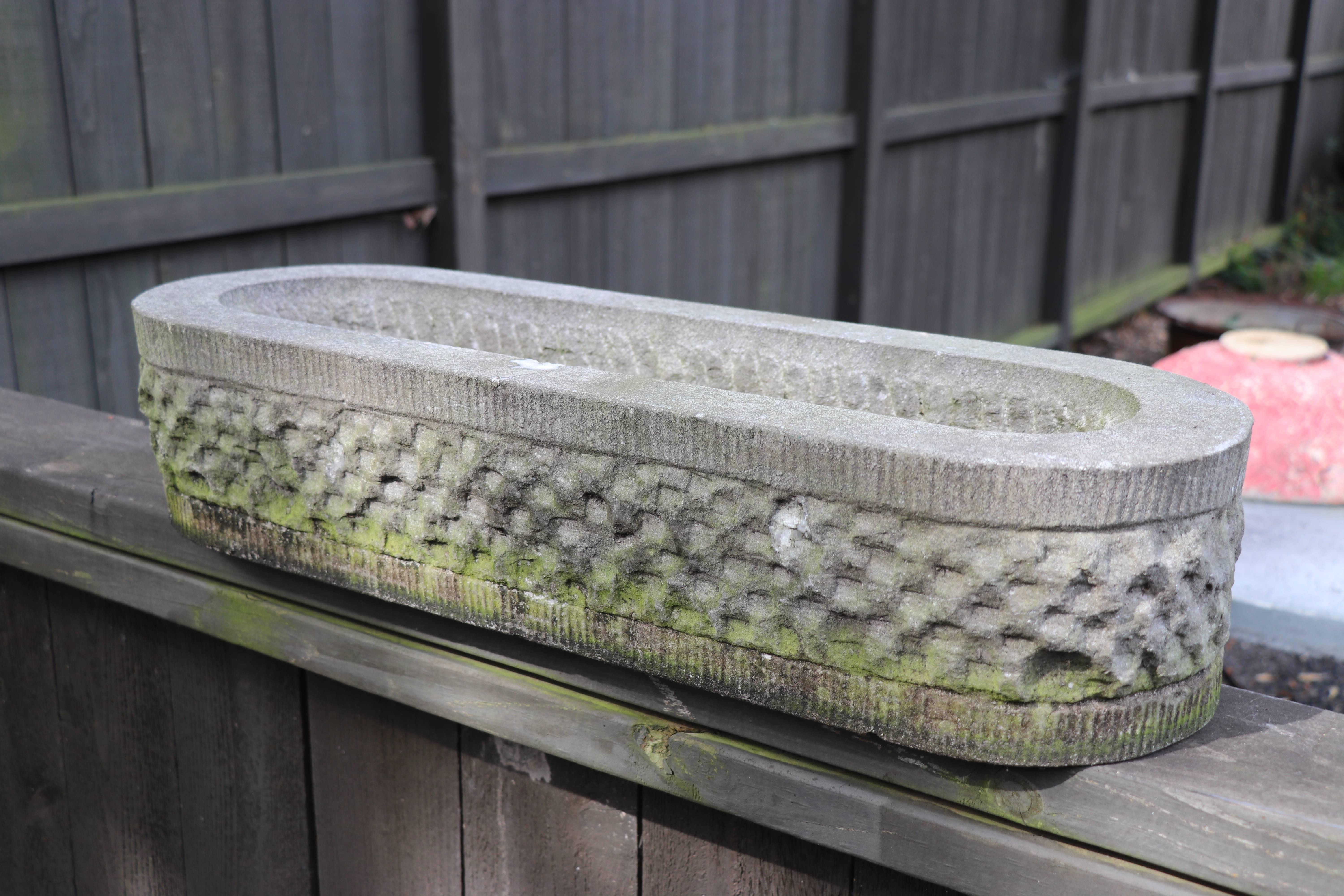 Hand-carved bluestone oval planter: vintage textured bluestone, or limestone, planter from Belgium. Heavy with hand-chiseled textured exterior resembling a basket-weave. Drainage hole drilled on one side. Circa 1940s. This planter evokes a sort of