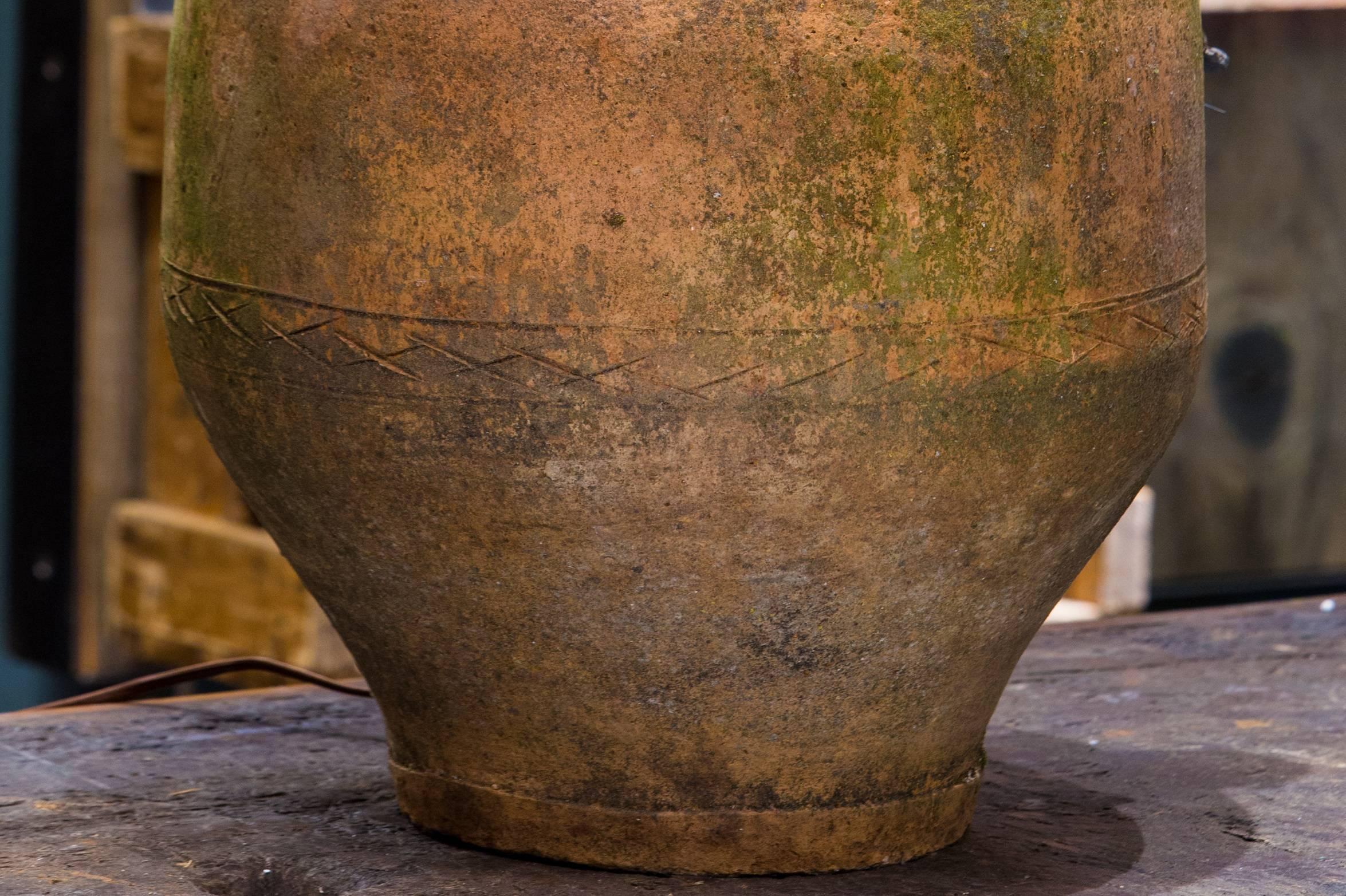 Terracotta vessel with two handles from Greece.  Originally used as an olive jar.  Newly wired in the USA with all UL approved parts and a wood top.  Beautiful patina and cross hatching detailing.  Hand-made.  Bulb not included.