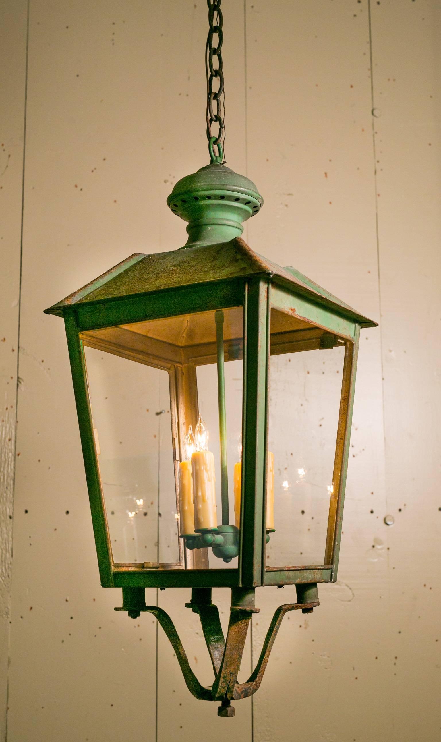 Pair of vintage iron lanterns with original green paint.  From France, circa 1920. Comes with matching chains and canopies.  Newly rewired in the USA with all UL approved parts and a four light candelabra cluster.  Price is for the pair.