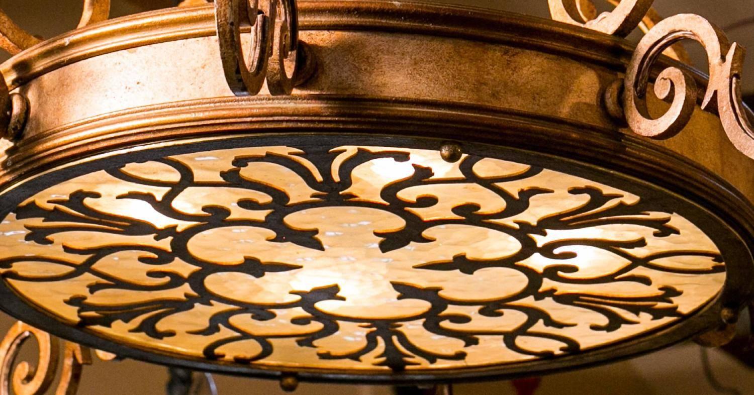 Decorative, scrolling iron-work with acanthus leaf detail at the top and glass bottom with cut-out metal overlay. Eight arms with candelabrum sockets and four internal sockets light up the glass. Newly rewired in the USA with all UL approved parts.