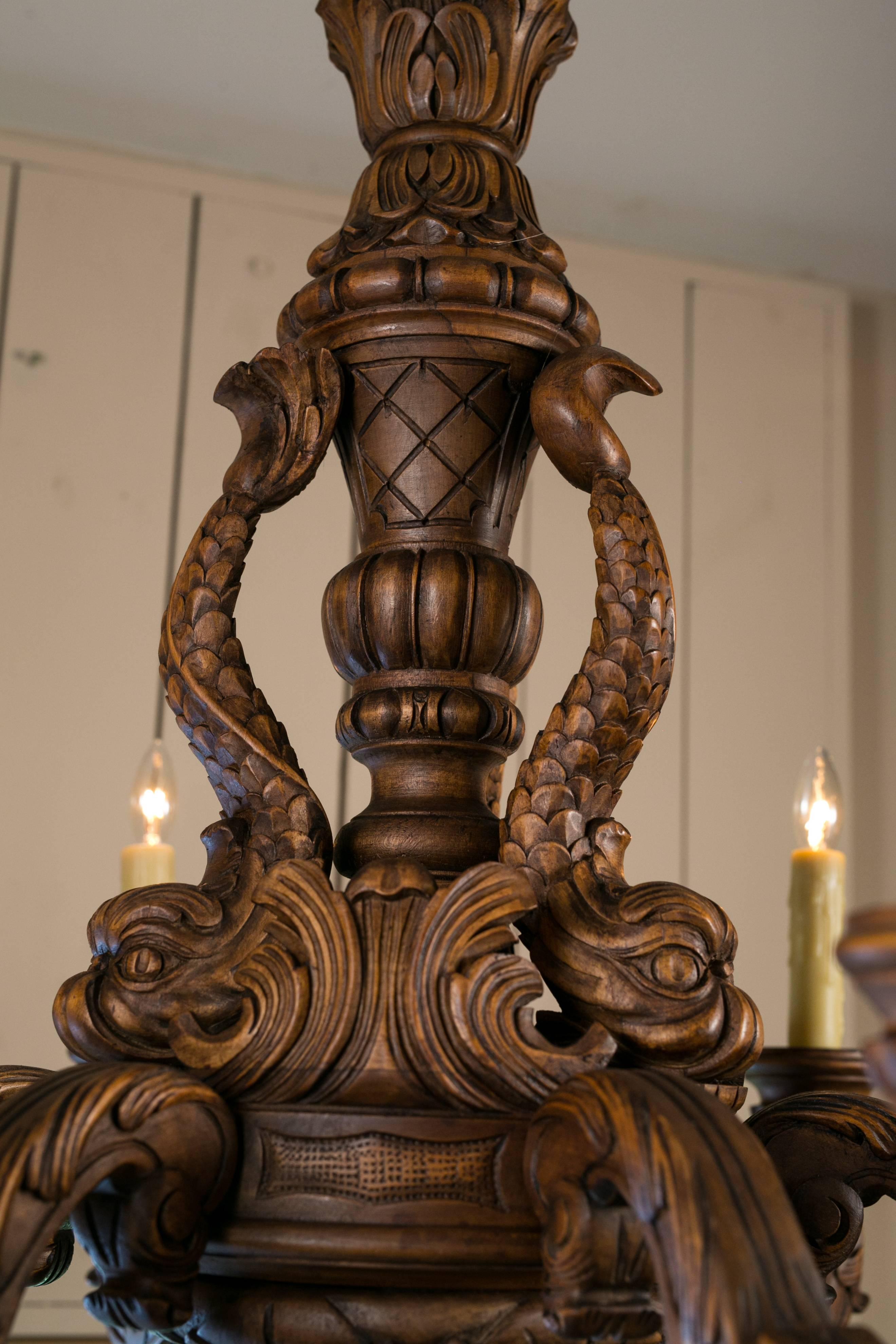 Six-arm, heavily carved wood chandelier from France, circa 1930. Beautiful color, expertly crafted with a dolphin motif on center post. It is built like a piece of furniture in the Rococo style.  Newly rewired for use in the USA with all UL approved