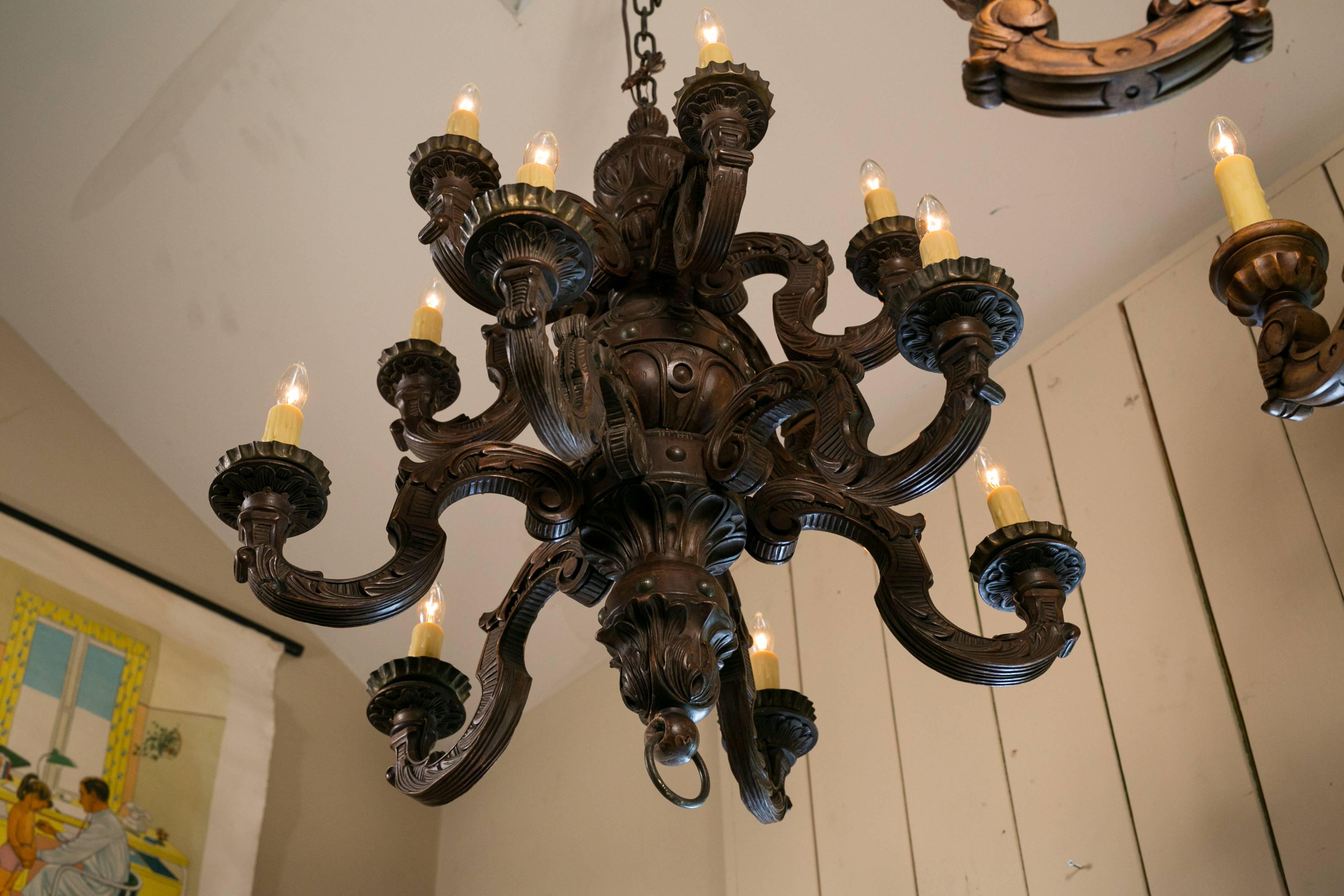 Beautifully hand-carved Baroque-style chandelier with 12 candelabra sockets and repetitive carving. Unusual shape with two tiers of lights. Newly rewired for use in the USA with all UL listed parts.  Has been previously repaired.  Comes with chain