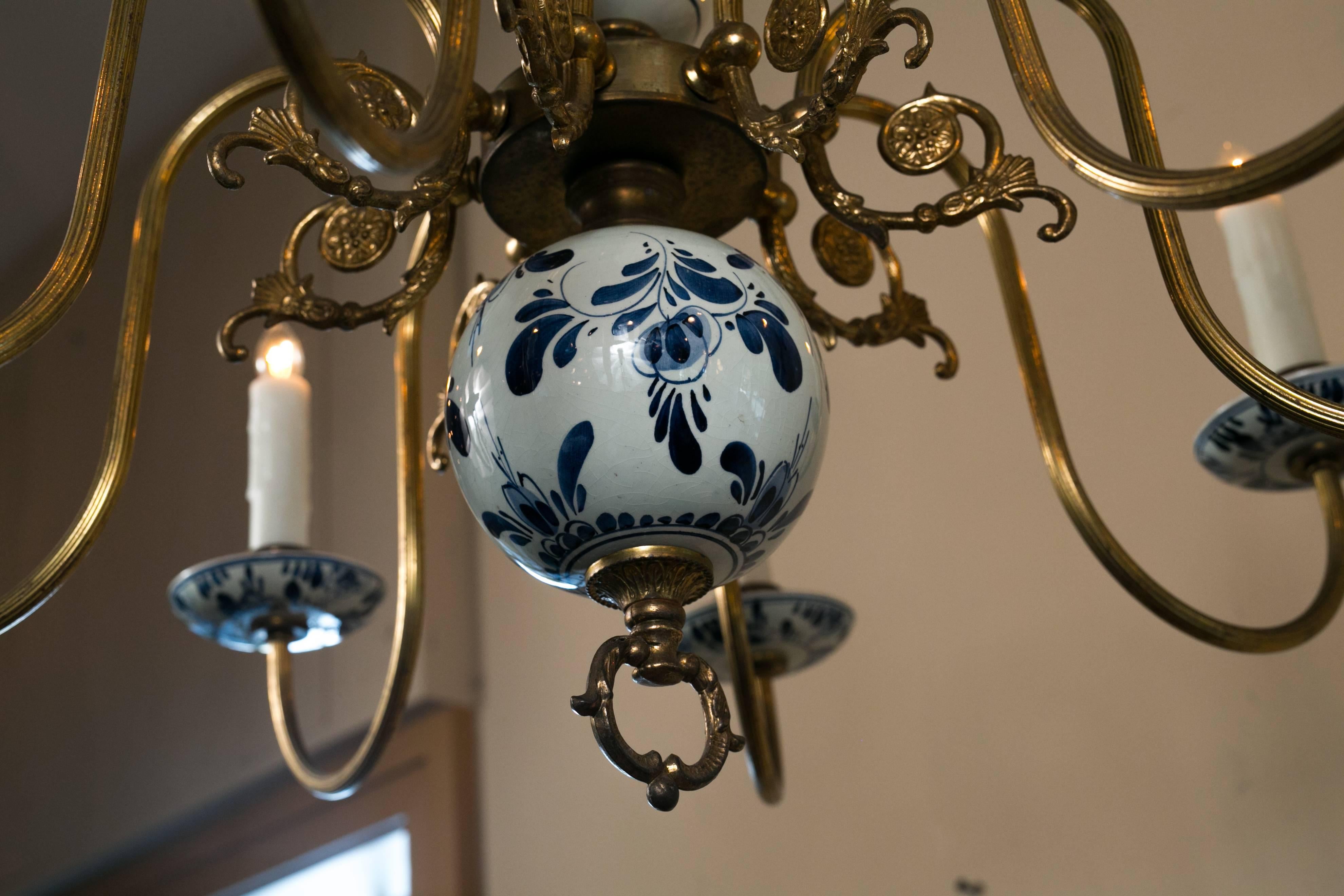Vintage eight-arm delft and brass blue and white chandelier. Hand-painted body and bobeche with interesting design on the arms. Newly rewired in the USA with all UL approved parts and eight candelabra sockets to give off lots of light. Comes with a