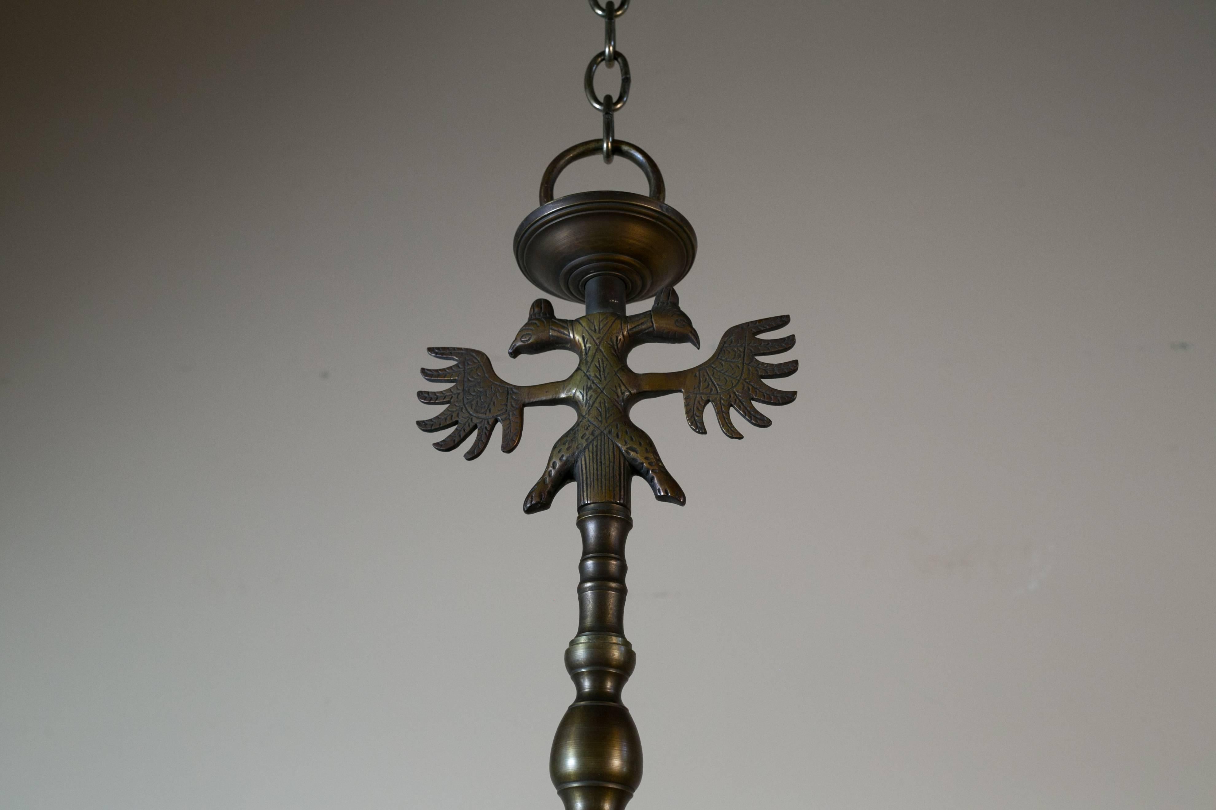 Vintage heavy bronze chandelier with eight arms from Belgium, circa 1940. Features a double headed eagle at the top and stylized faces on the arms. Beautiful patina on the bronze and a Classic, timeless design. Unusual features like the flat dolphin