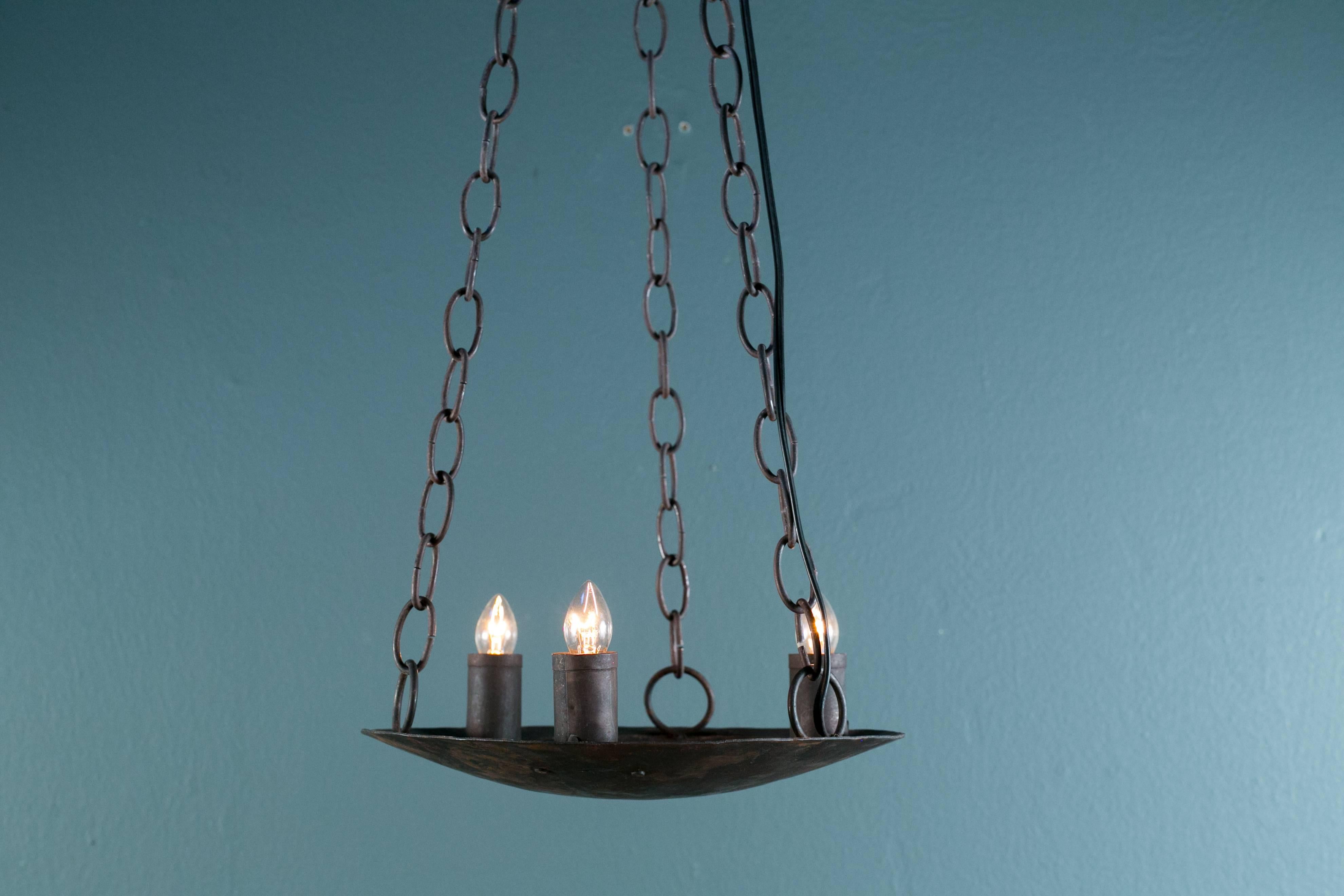 Simple and primitive hand-crafted iron light newly wired with all UL listed parts and three candelabra sockets. Metal candle sleeves on the sockets. Comes with three, three foot lengths of chain above the fixture that connect to a three-hooked