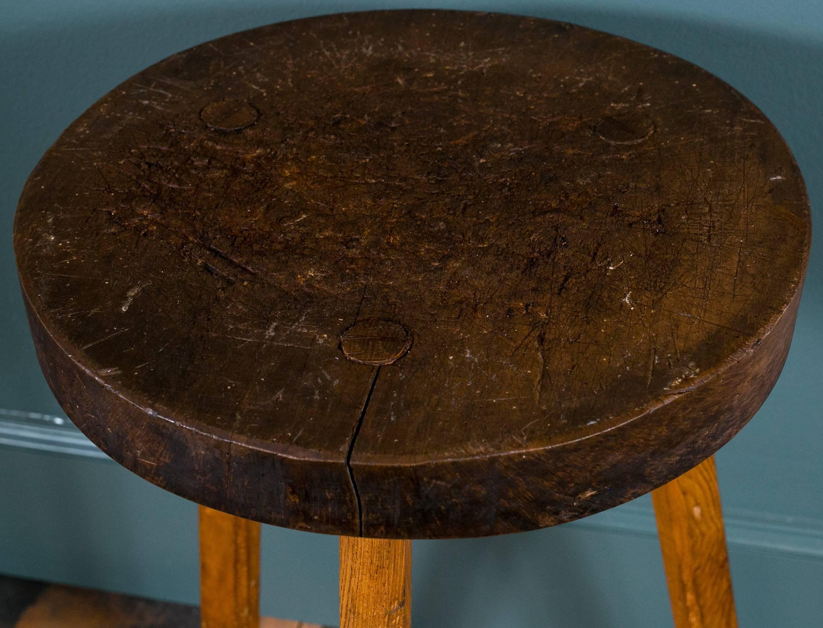 Three-legged chopping block with thick round top from Belgium. Wonderful texture on the top from use and round pegs where lit attaches to base. Diameter listed is of top. Leg splay is approximately 22