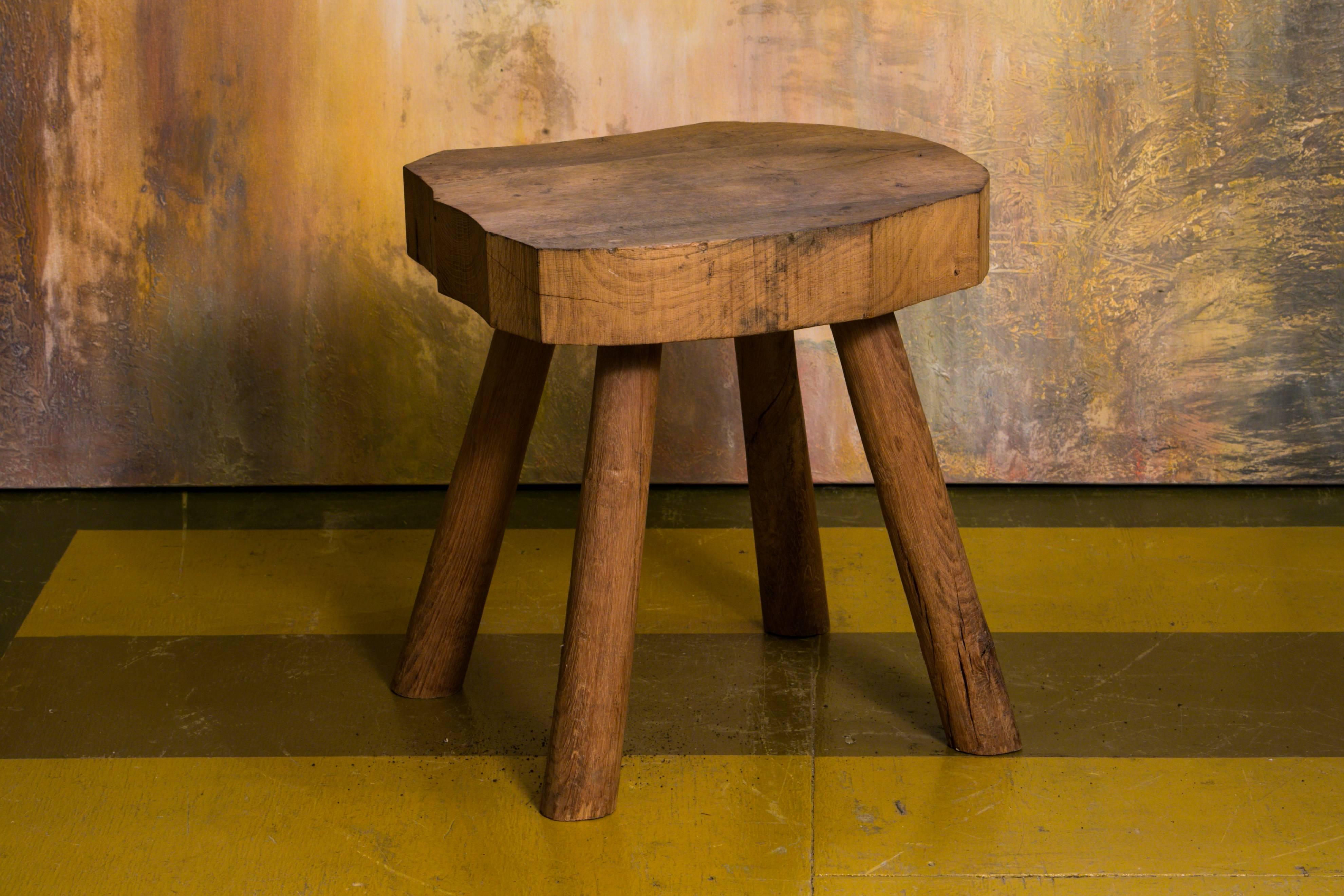 Rustic, Primitive wooden stool with four legs and a thick wood top.
Charming and handcrafted. Would make a great low side table.