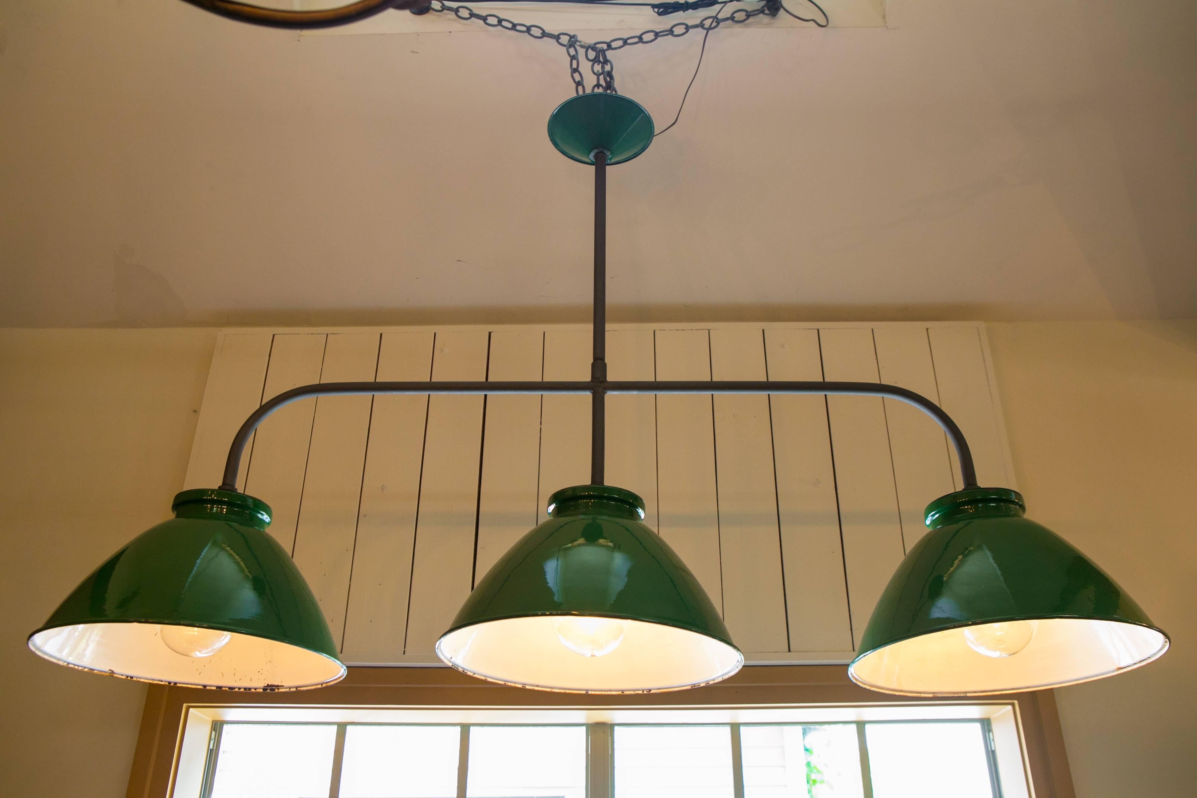 Our exclusive design, this three shaded light is constructed from vintage French green enamel factory lights and an iron body. Custom green vintage enamel canopy cover attached to the rod. Perfect for a pool table or over an island. Shades are from