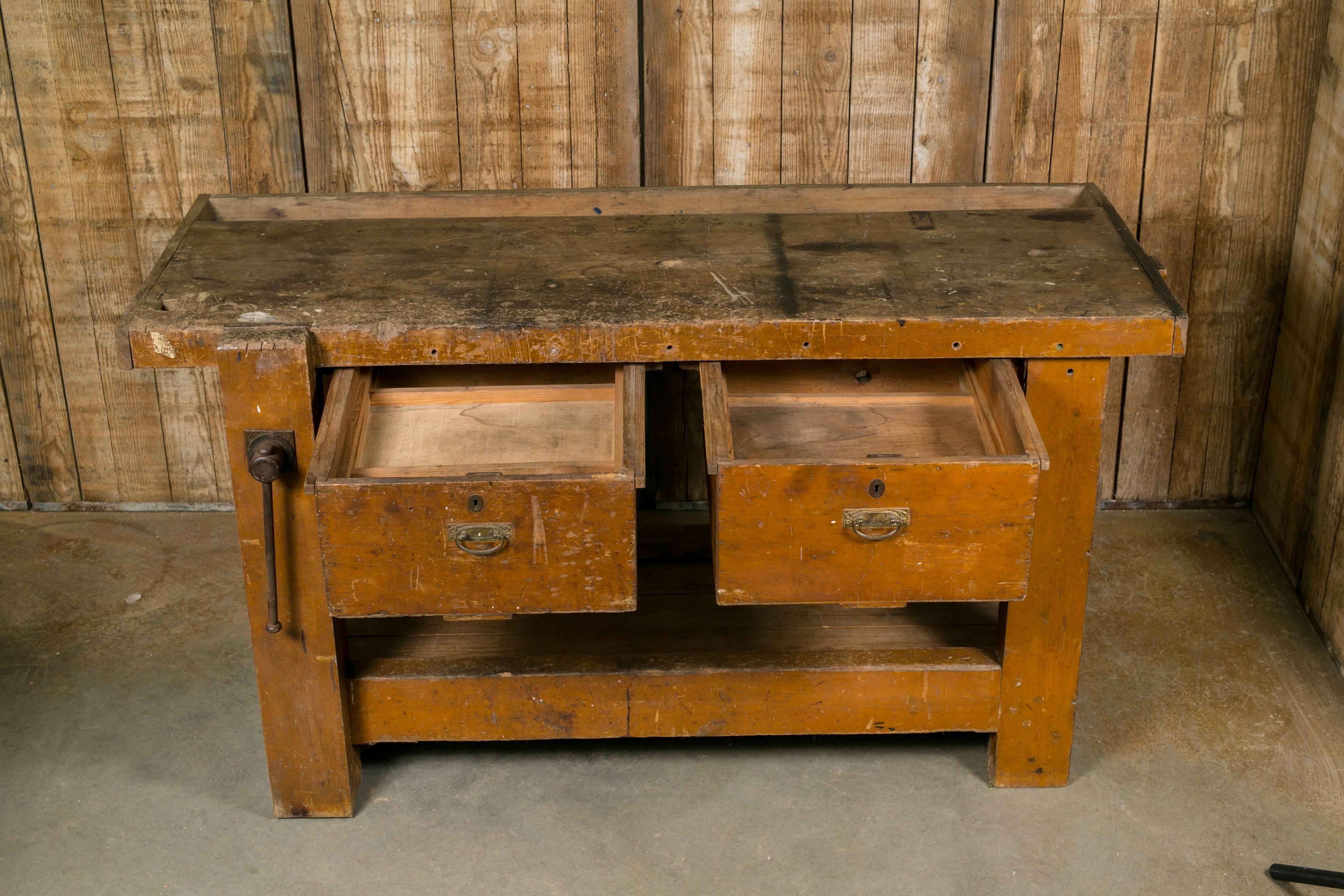 Belgian work bench with vise clamp on the front and two drawers. All original with a shelf below. Great for a kitchen island or console. Beautiful worn, honey colored wood with rustic look.