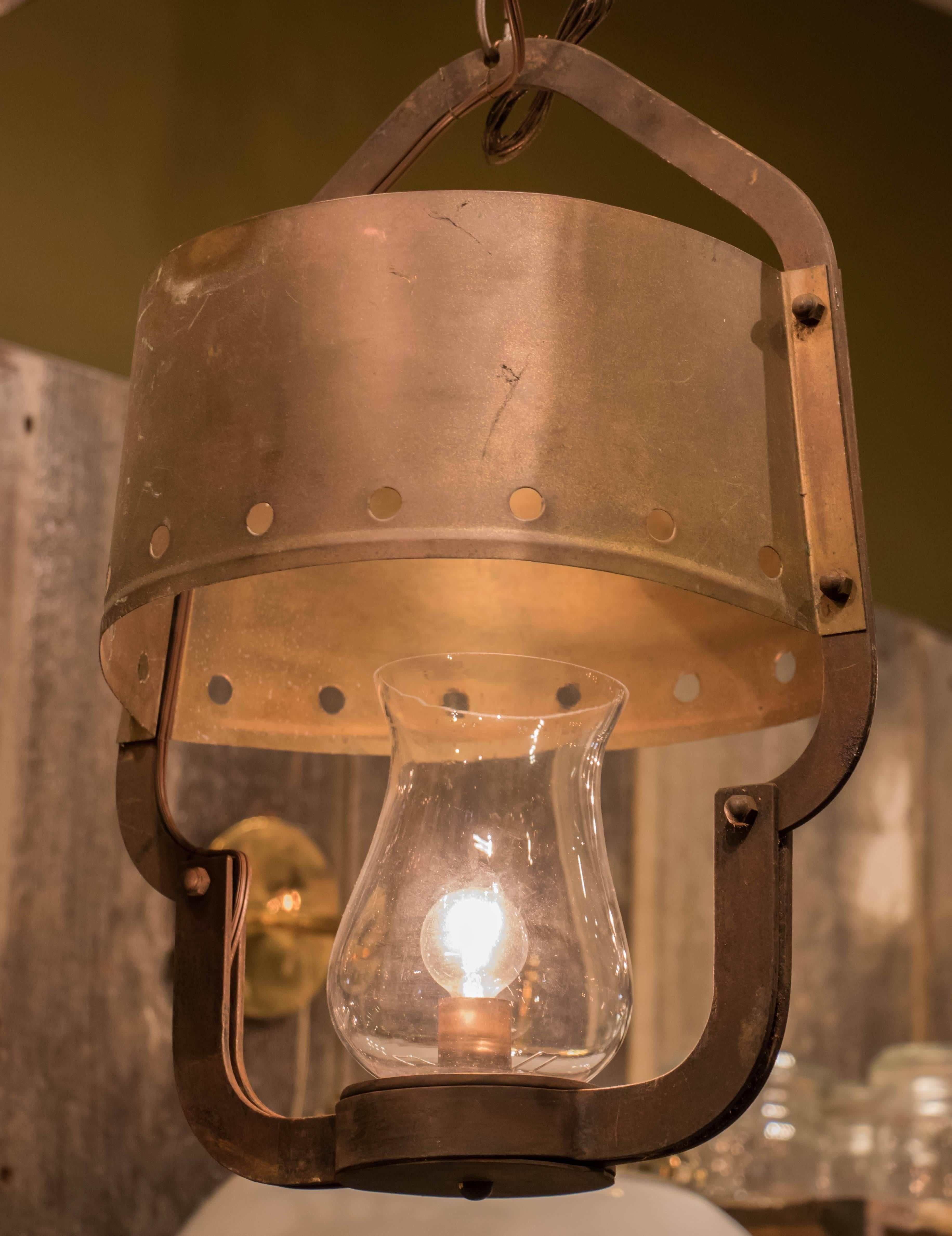 Arts and Crafts style vintage iron lantern with perforated brass sheet metal shade and blown glass hurricane, circa 1930s. Newly wired with all UL listed parts and a single upright candelabra socket. Comes with matching chain and canopy.