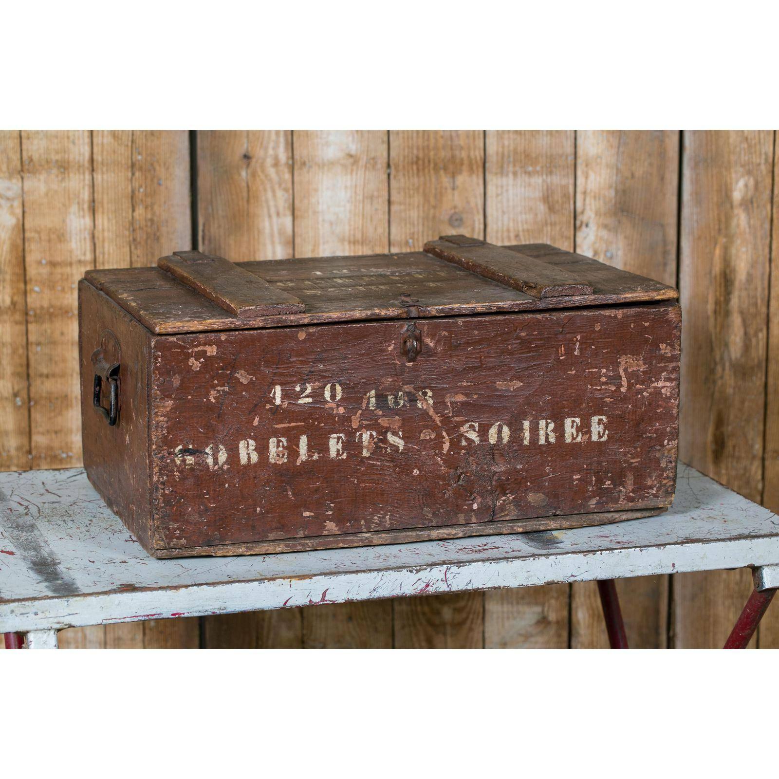 Curious antique wooden campaign crate/ trunk with hinged lid and metal handles on the sides. All original paint in oxblood red color with white stenciling. Features original paper divider inside with original (60 in total) cordial glasses. Was used