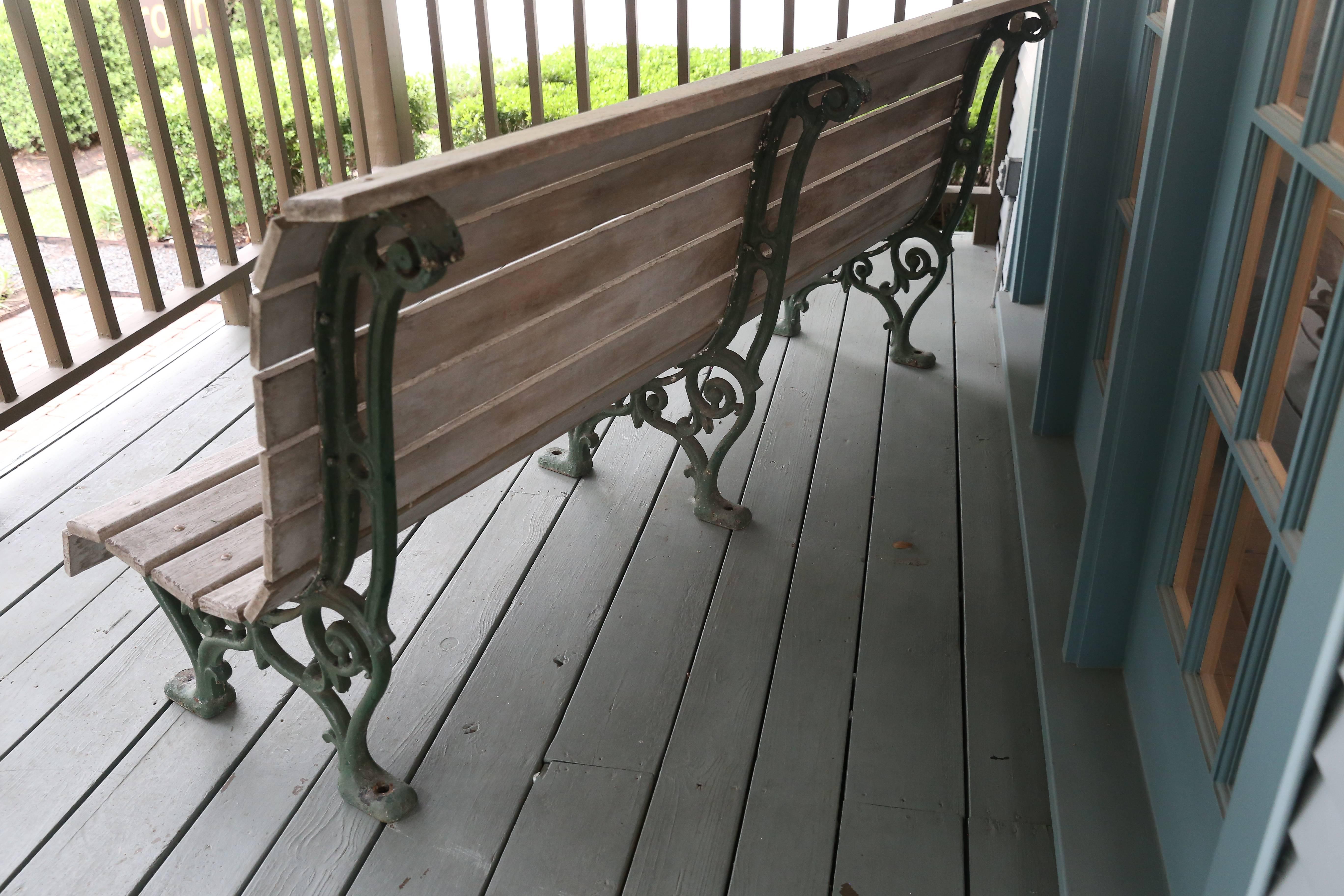 Large antique park bench from Belgium, circa 1910. Light colored curved wood slats, painted light grey, with enamel painted green iron legs and frame. Pretty decorative iron scroll work on the legs and back supports. Sturdy, heavy and comfortable.
