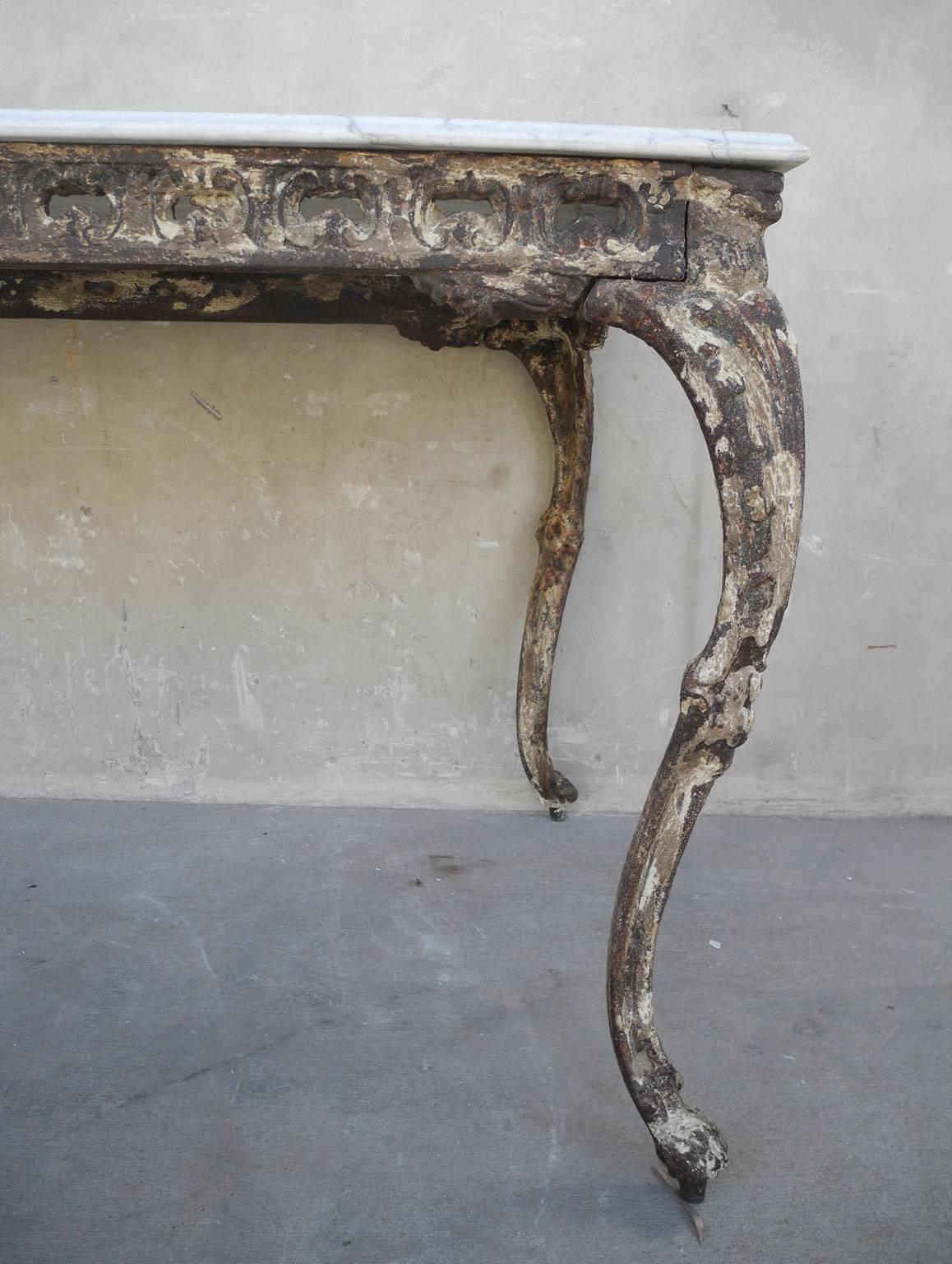 This is a beautifull reclaimed 19th century Italian iron and marble table from an Orangerie. The bottom is made of antique iron while the top is a large piece of white marble. It is luxurious in feel and very sturdy. It has intricately carved legs