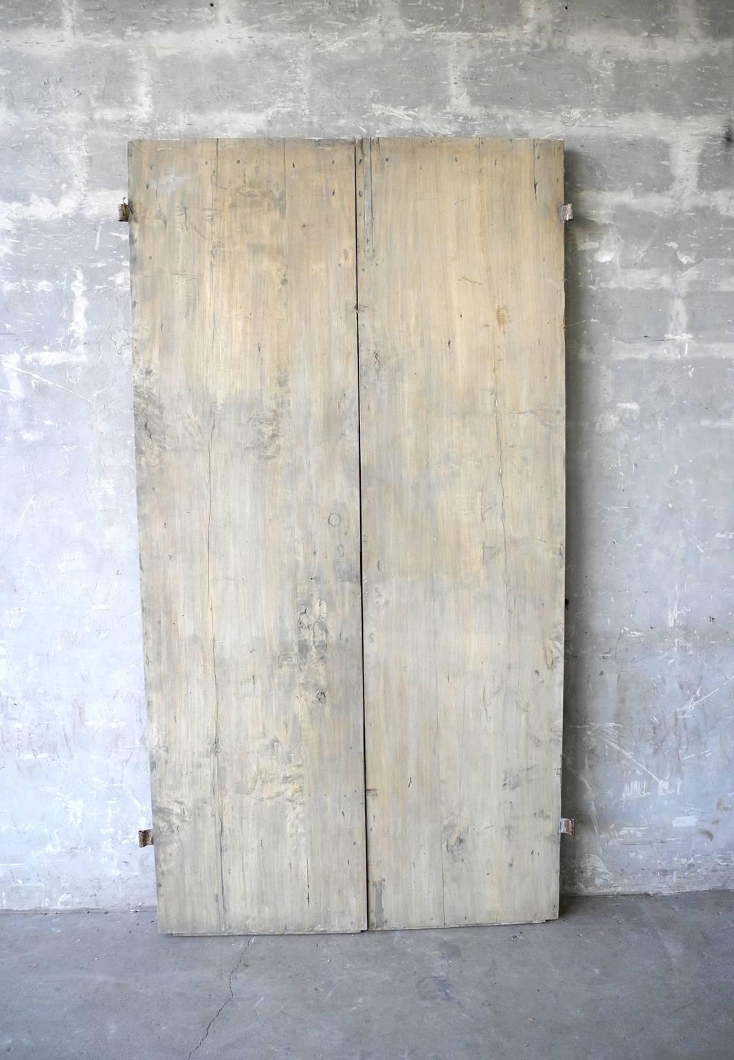 This gorgeous pair of antique 18th century doors from a property in Bologna, Italy have beautiful carving and original antique hardware. The doors have been stripped of color, giving them a natural and lovely finish. The doors are also very sturdy