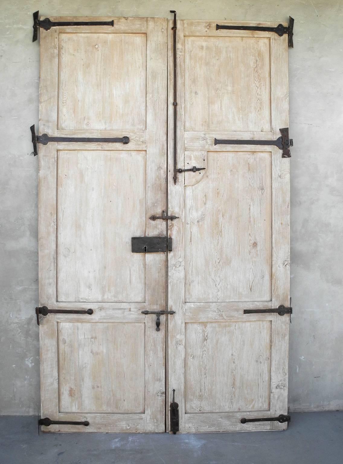 This pair of 18th century Spanish entrance doors are enormous in stature. They make for the perfect entrance doors. They have been reclaimed, so they have a been bleached and painted brown. They include original hardware and carved details.