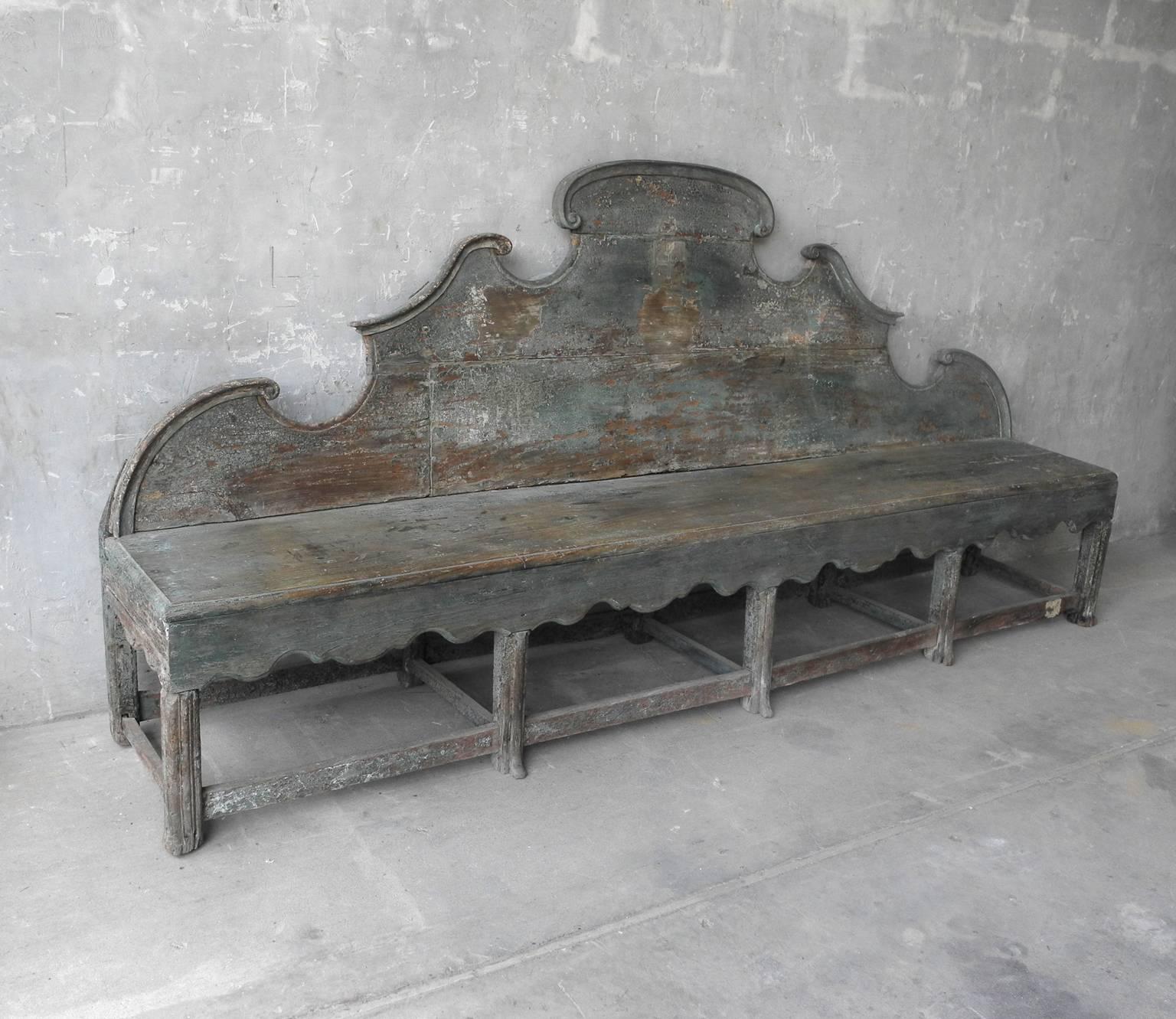 This is an intricate and lovely 18th century Italian bench from a convent near the Swiss border. The bench boasts great length at almost 107 inches wide. It has a beautiful back panel that has lovely detail, as well as carvings under the seat. The