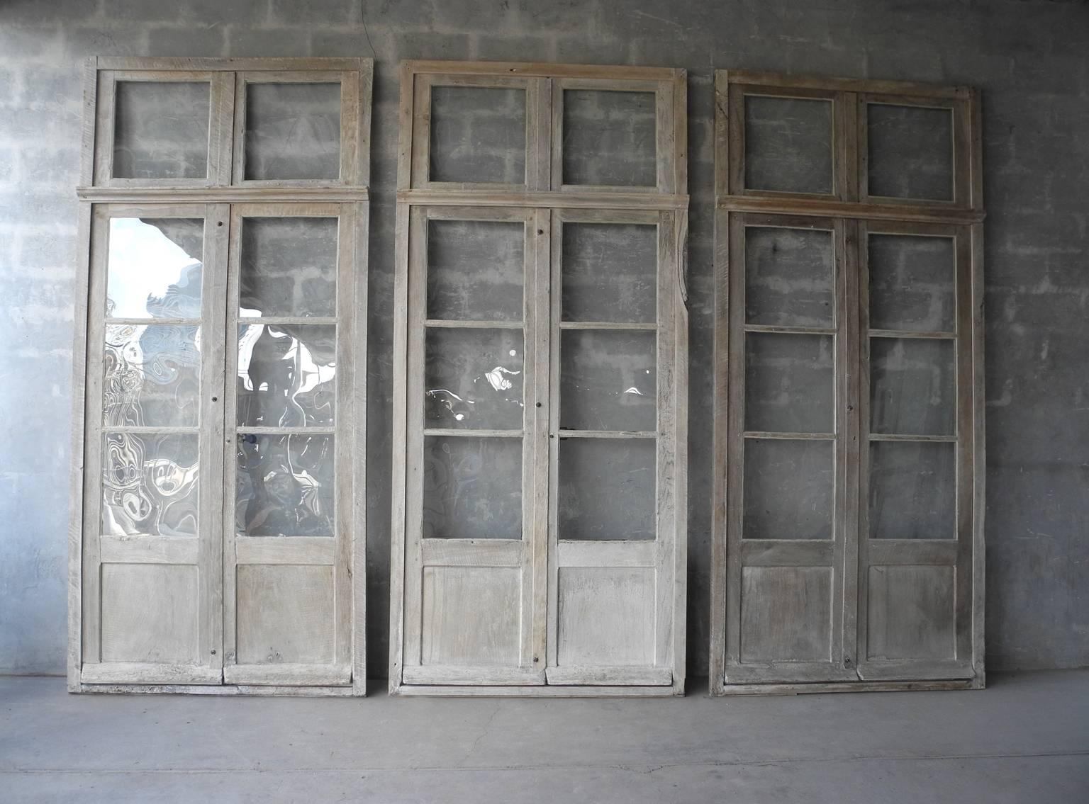 This is a gorgeous group of very large wooden windows from Sisteron. They all include original reclaimed hardware and wood. They have been bleached to give them a natural finish. All glass has been replaced, making them a perfect addition for either