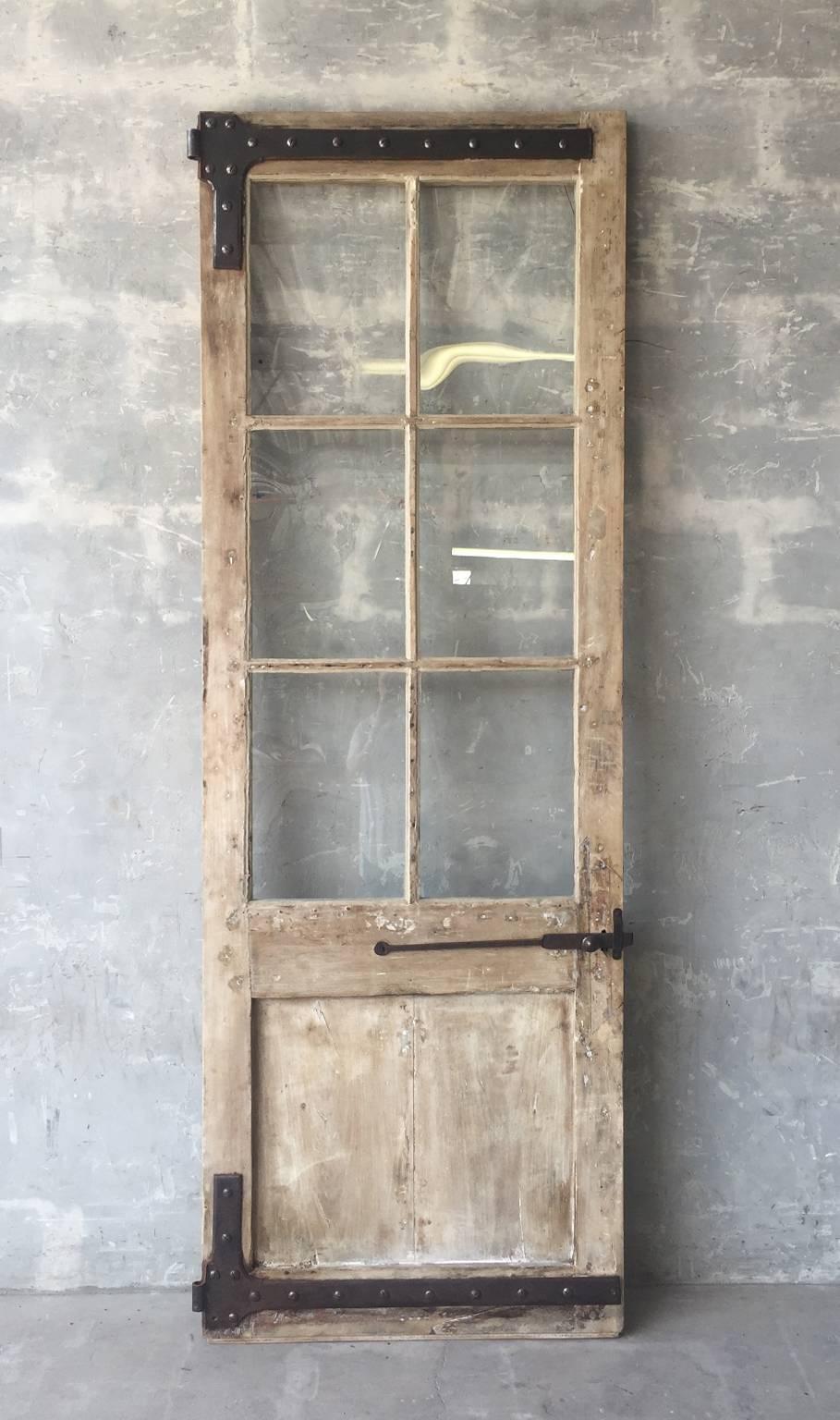 This is a single, fabulous antique 18th century walnut door from a storefront in the village of Lodere in the Languedoc region of France. This is a single tall door with six glass pieces. There is a carved crest on the bottom. Original reclaimed