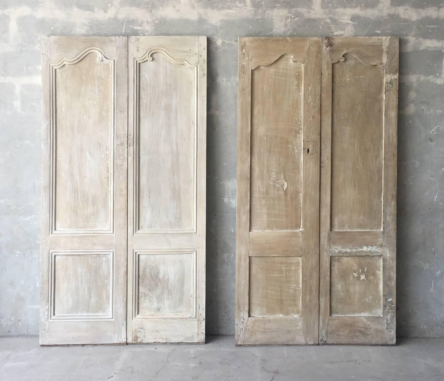 This is a lovely set of two pairs of antique cabinet doors. They boast reclaimed hardware and a natural wood finish. This small set is from the 18th century from a Maison de Ville in Beziers, France. They would perfectly flank any casual living