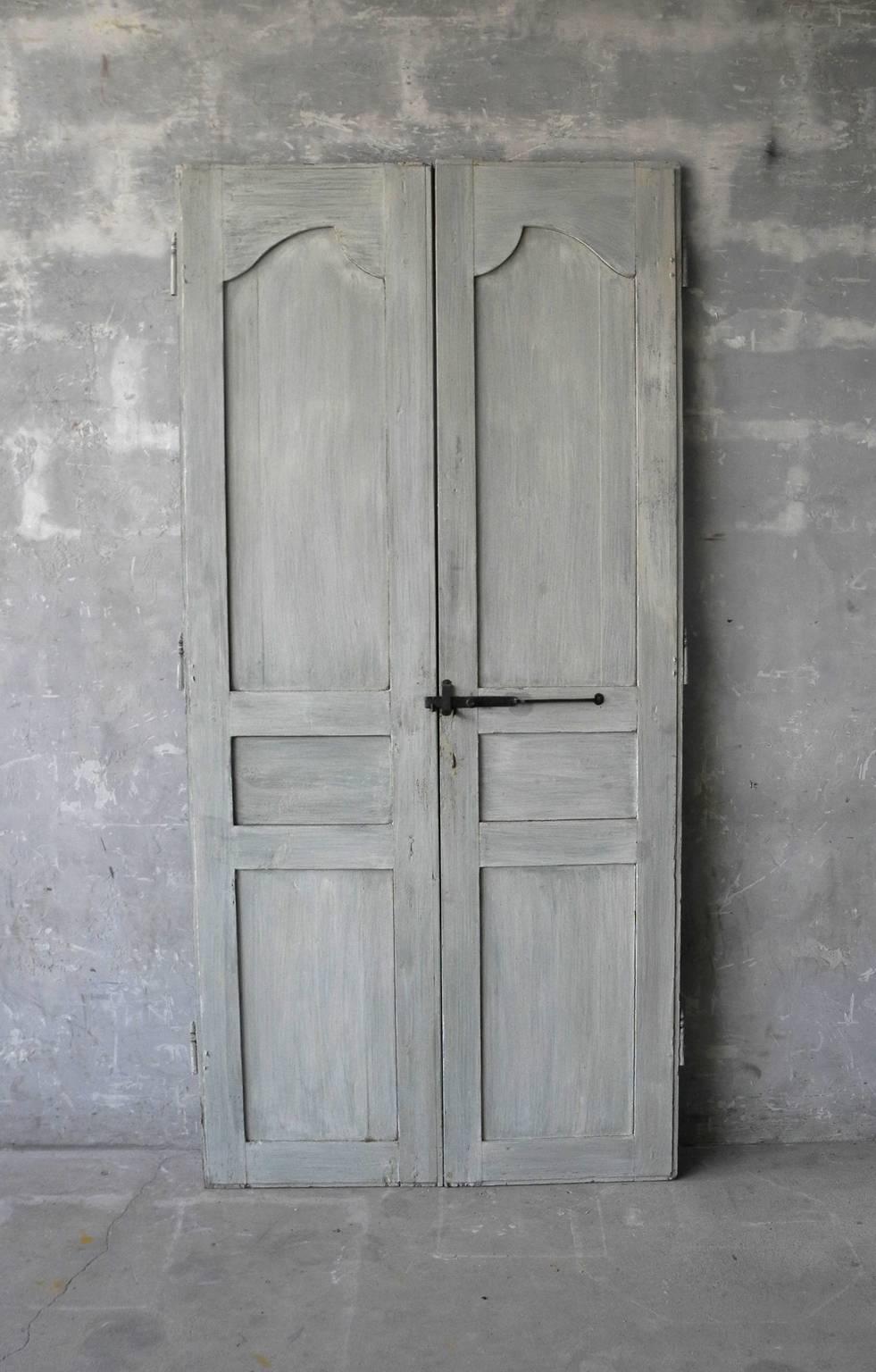 This is a wonderful antique pair of blue Louis XIV communication doors. They are a matching set, perfect for a closet or pantry door. They include original reclaimed hardware made of iron. They are simply paneled, true to their time period.