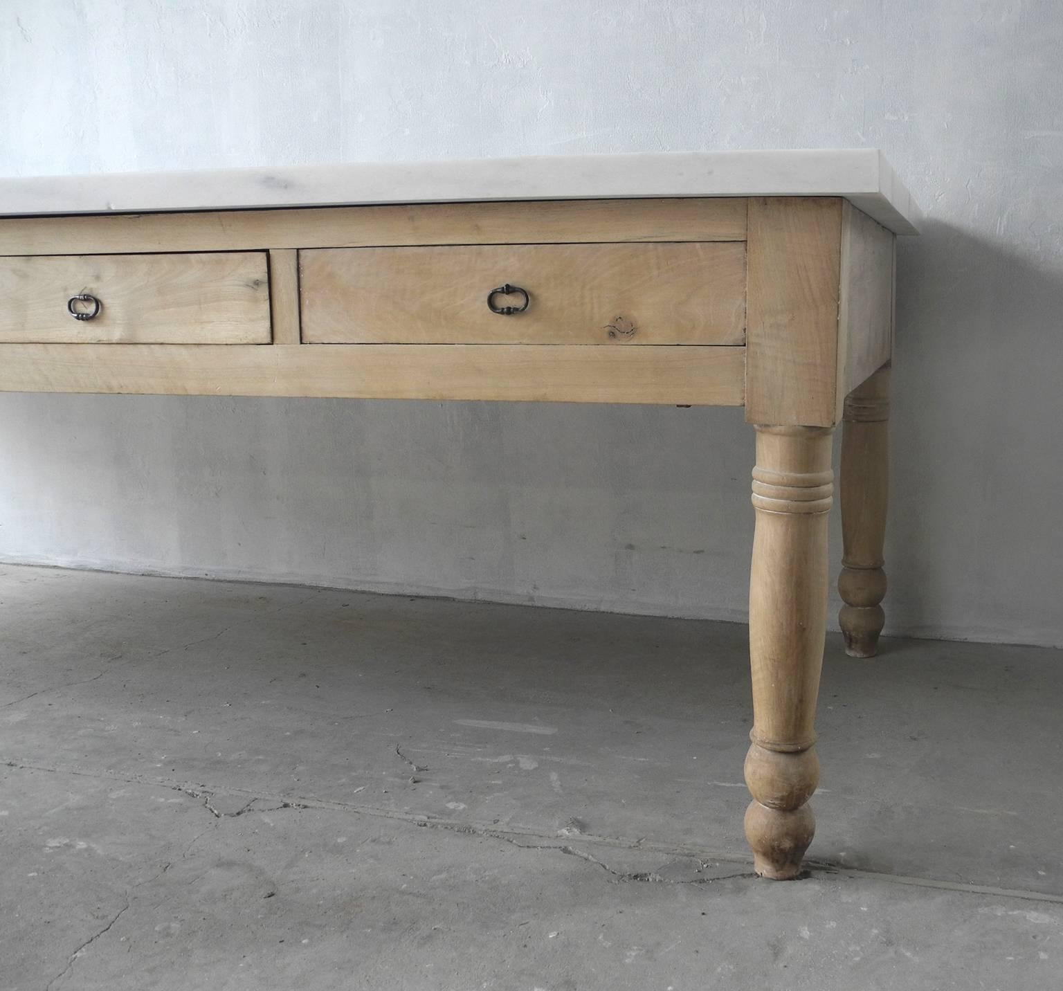 This is a grand and wonderful antique walnut table base with carved legs and drawers. It is from the late 19th century. It boasts a beautiful natural finish and reclaimed antique iron hardware. It also has a fabulous white marble top made from our