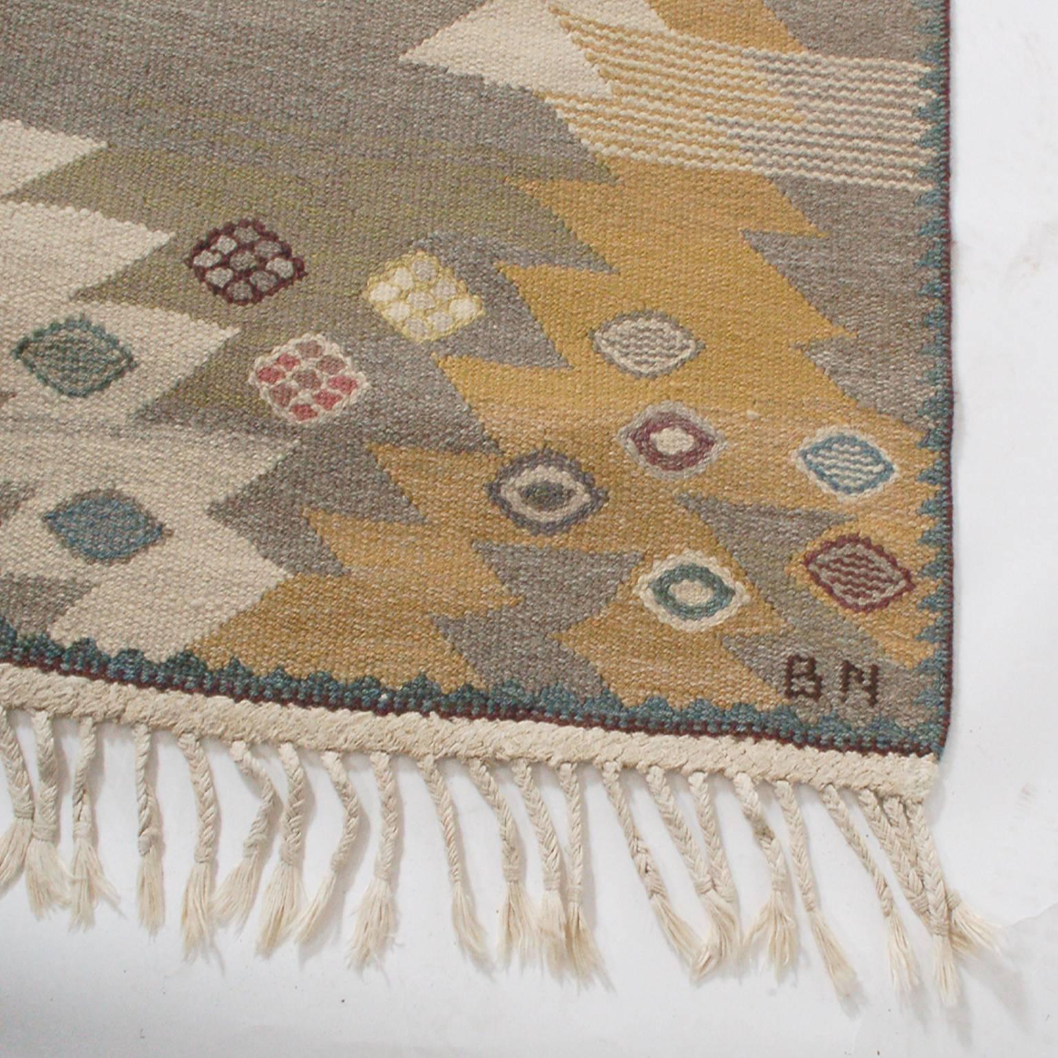Flat-weave rug created for the Swedish rug company Marta Maas-Fjetterström in the 1950s, by their premiere designer. Retains original fringe. Signed with artist's initials, BN and MMF at the bottom edge.