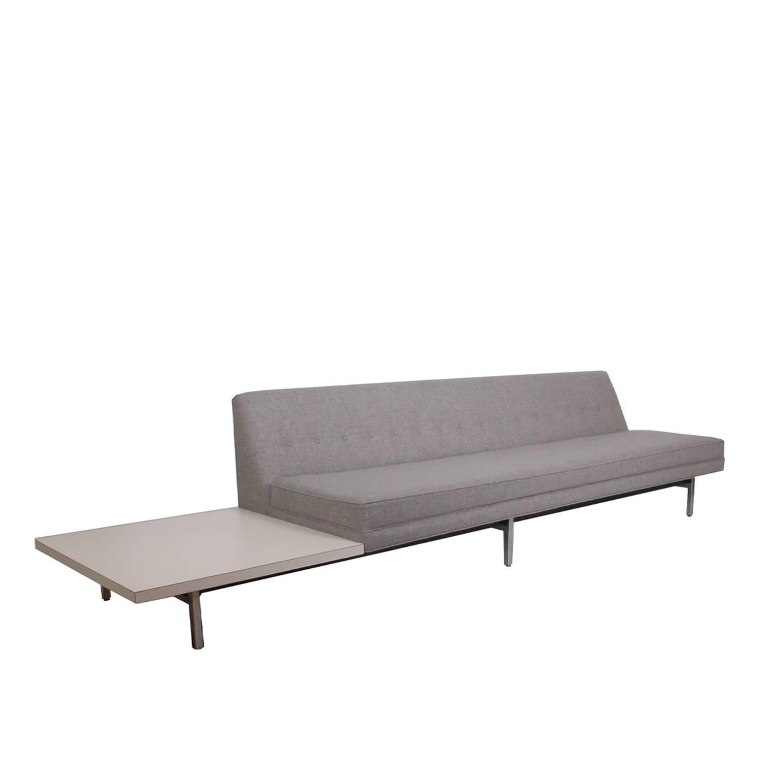 Three-seat sofa with laminate side table attached. Six square brushed steel legs. Previously upholstered. With round metal tag.
Made by Herman Miller.

 