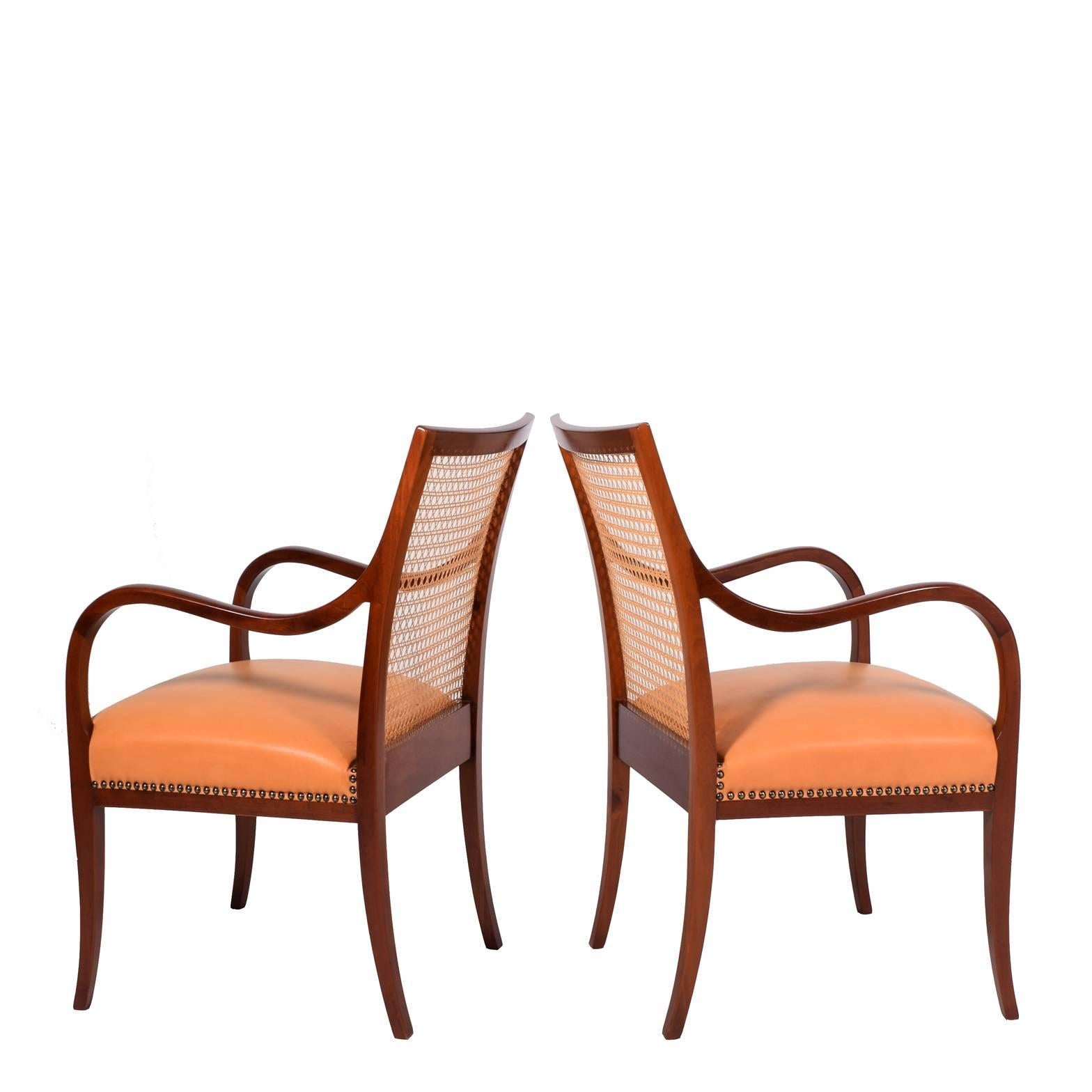 Elegant pair of armchairs with cane back and leather seat on solid Cuban mahogany frame. Curved arms and legs; seat with brass nailhead detail. Seat reupholstered in natural Vegeta leather. Made by Frits Henningsen Studio.