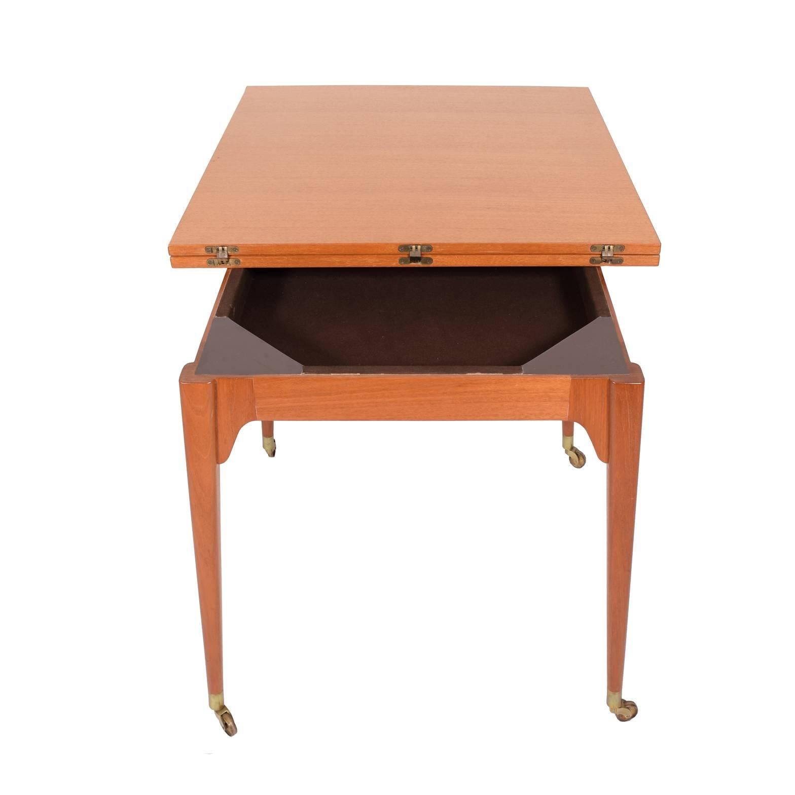 Flip-top table, mahogany top on solid mahogany legs with brass feet on casters. Top pivots and unfolds. Measures: Extends to 68