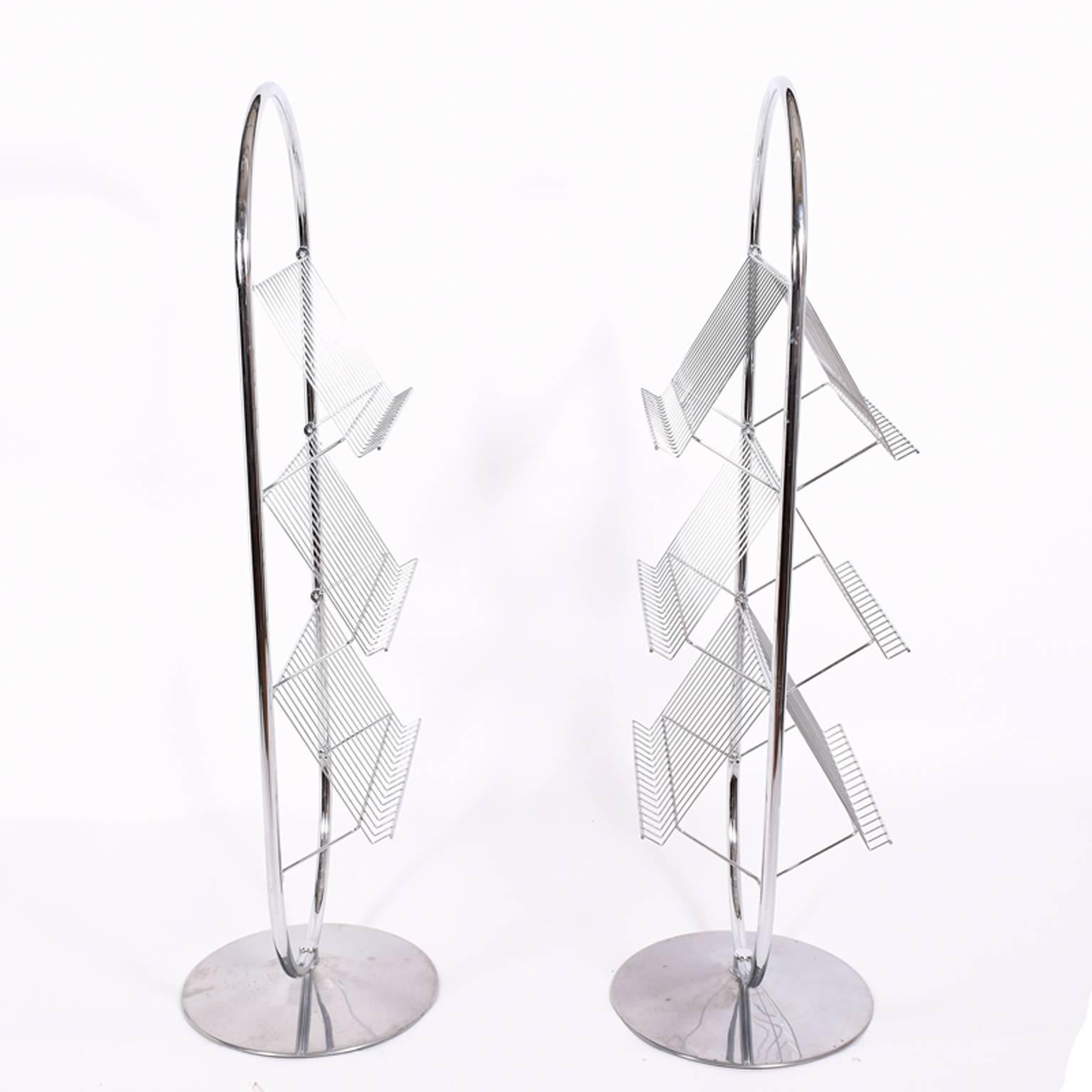 Two circular chrome frame and racks on polished aluminium bases. One rack can be displayed from both sides, other rack display on one-side only. Signed with label.