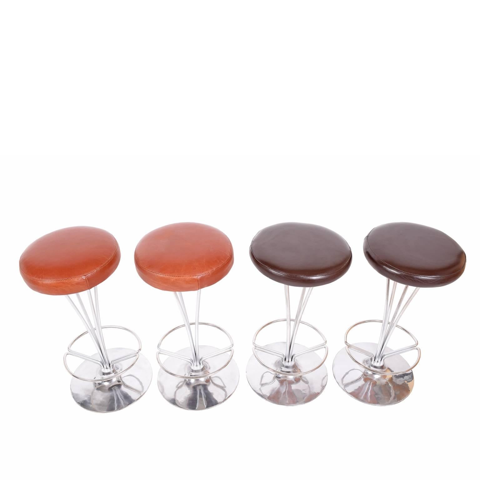 Two pairs of rare, hard to find counter height stools with steel frame and foot rests on aluminum disc base. Brown and orange leather upholstered seats. Made by Fritz Hansen. Sold in pairs only. PAIR ON THE LEFT SOLD 