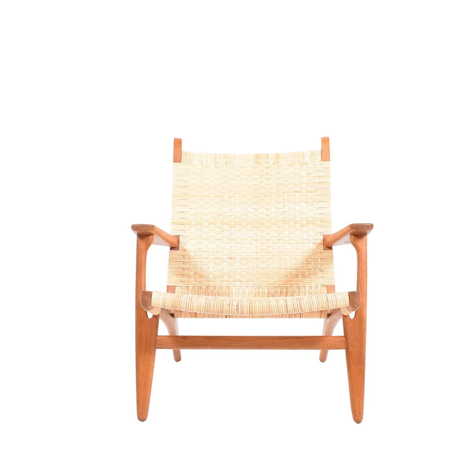 Vintage CH27 lounge chair by Hans Wegner with woven cane back and seat on oak frame. Signed underneath arm. Designed for Carl Hansen, 1950.
 