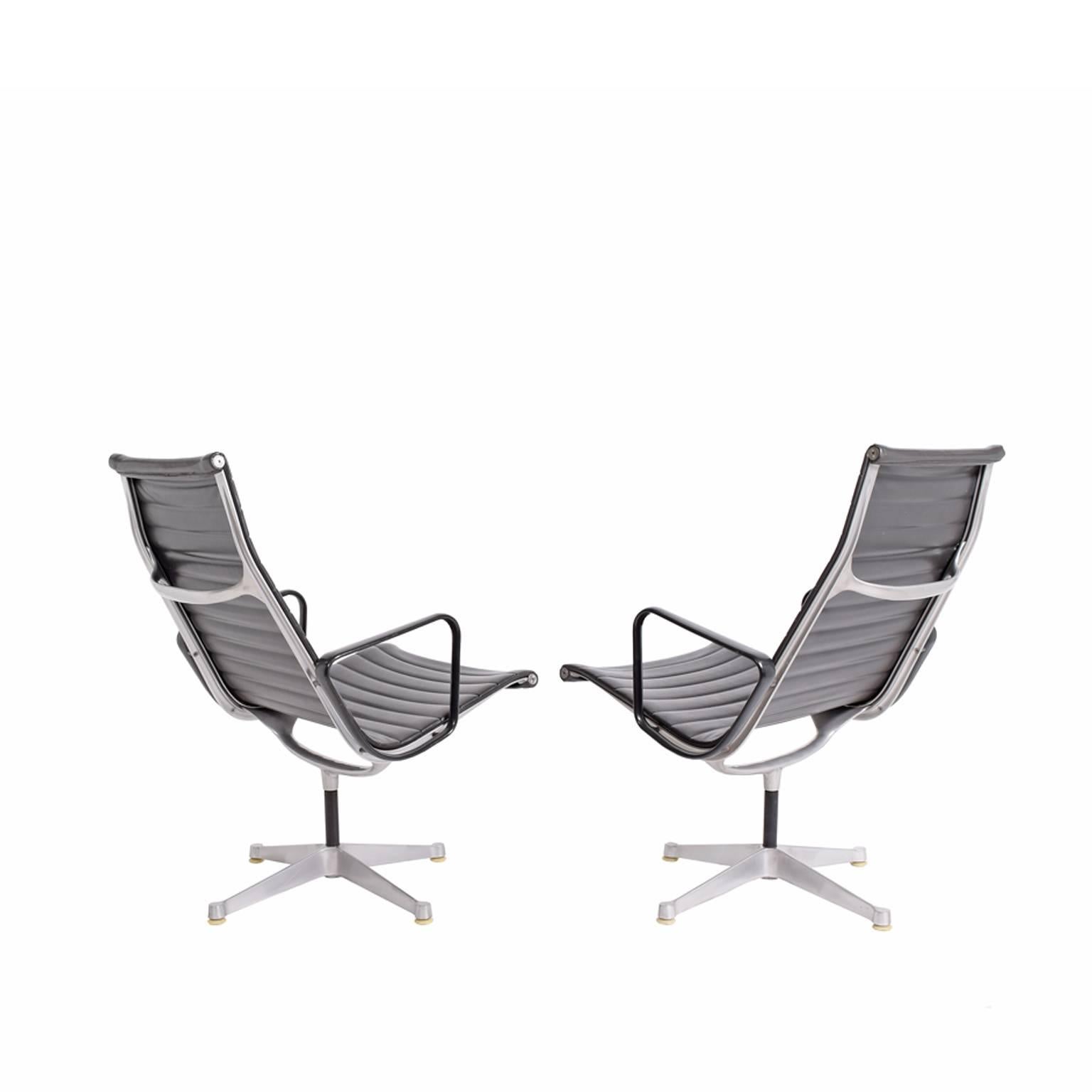 Early Eames Aluminum Group swiveling lounge chairs with first production bases, black painted arms and black vinyl seating. Herman Miller stamp.