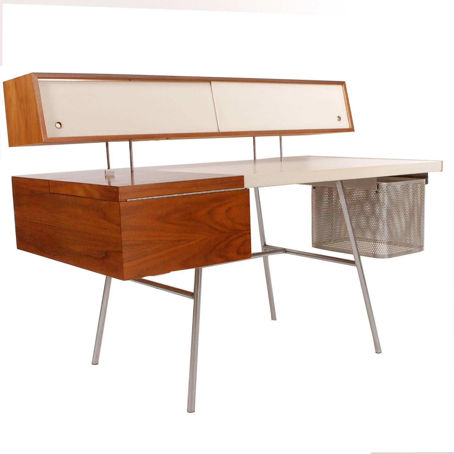 Walnut with original custom white leather writing surface and sliding floating doors, small drawers in maple. Storage and drop down typing table with original perforated aluminum file drawer. On steel legs. Made by Herman Miller.