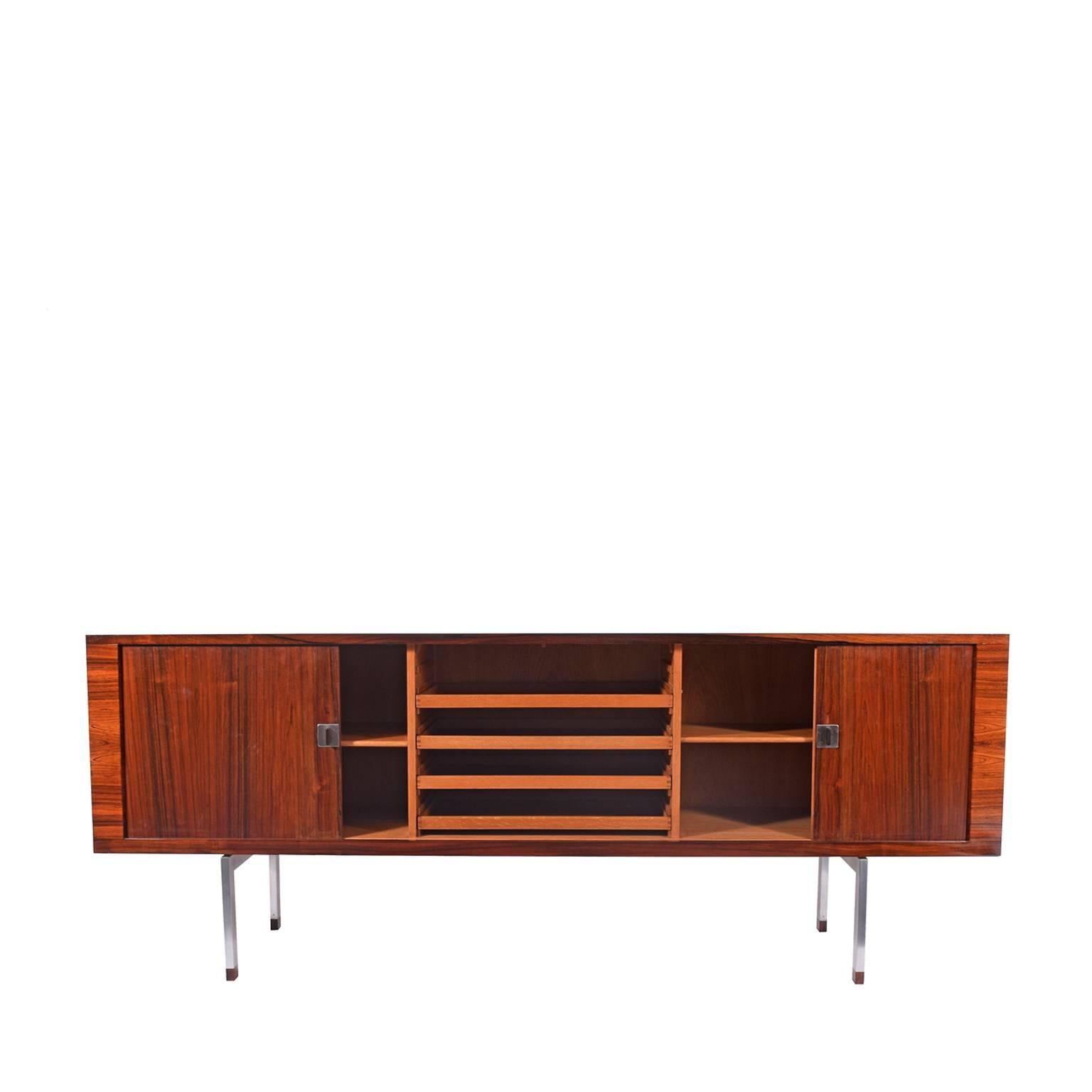 Wegner cabinet in rosewood with chrome legs and rosewood feet. Two adjustable shelves and four trays in the middle in oak. Danish quality manufacture's label, tambour sliding doors.