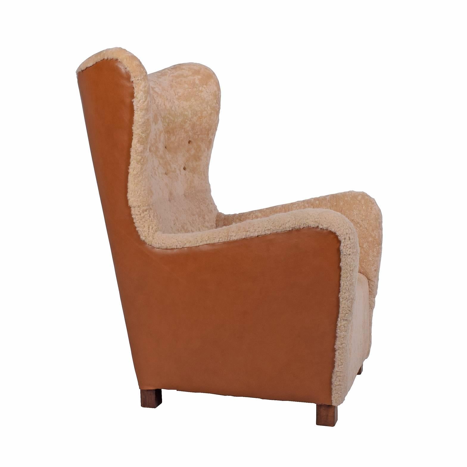 High back easy chair upholstered with leather on back and sheepskin on front with solid oak legs. In Fritz Hansen catalog from 1942.