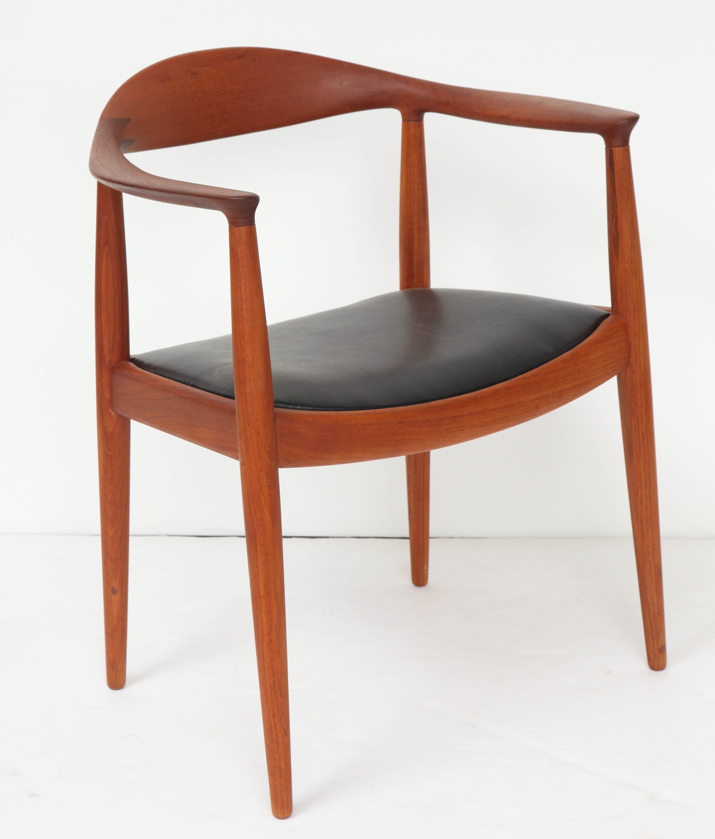 Solid teak frame with finger joint connections on back with black leather seat.  Marked JH.