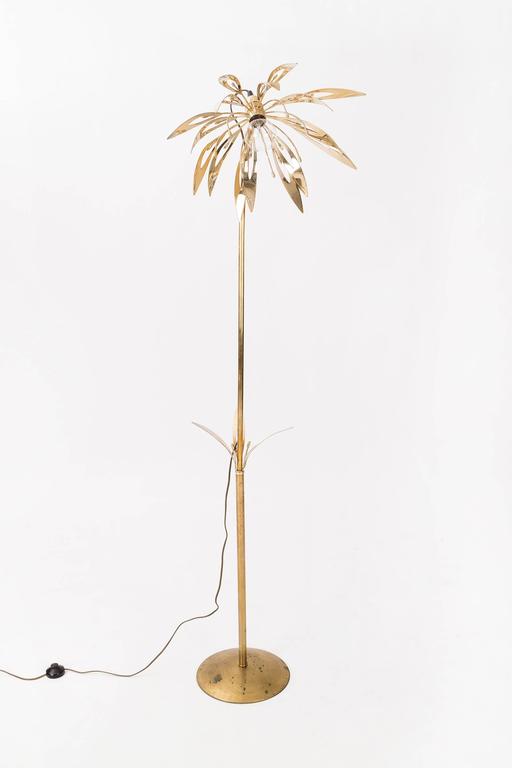 Brass floor lamp features cut-out petals and leaf details.
Has exposed lighting element and takes multiple bulb styles, shown here clear bulb.
Base has spotted patina consistent with age.
