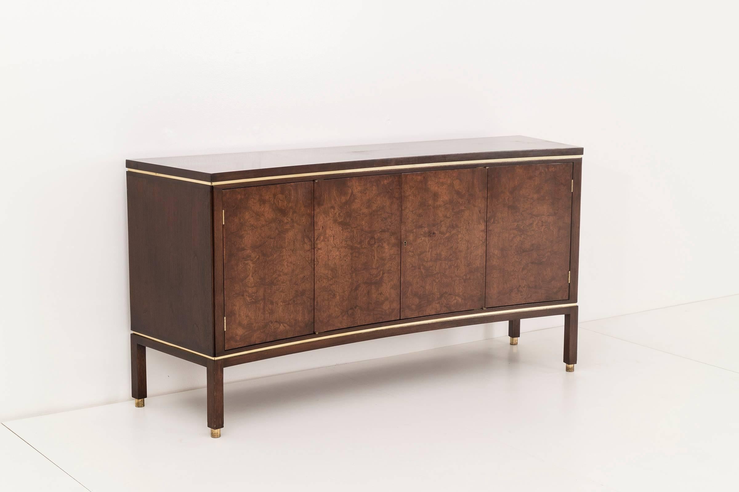 Edward Wormley for Dunbar. This curved-front cabinet is constructed from burled maple doors on a walnut case with brass trim detail and brass feet. The minimal curved front is free of pulls and instead comes with Dunbar "D" Key. The