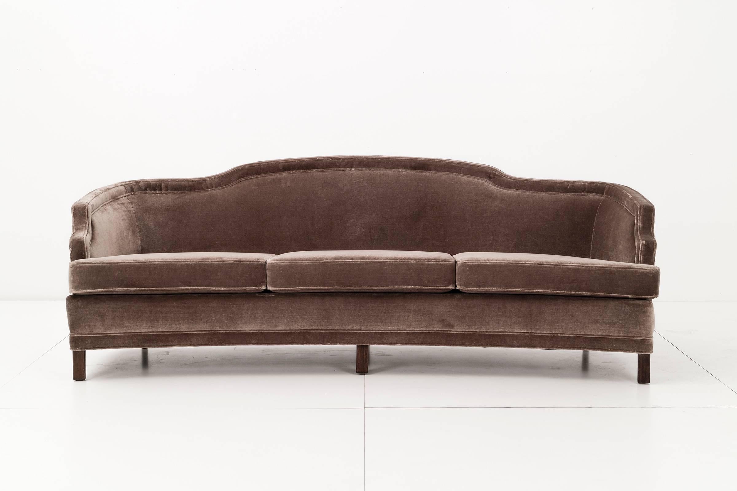 Newly upholstered in velvet. Curved sofa with sculptural lines. Walnut legs.