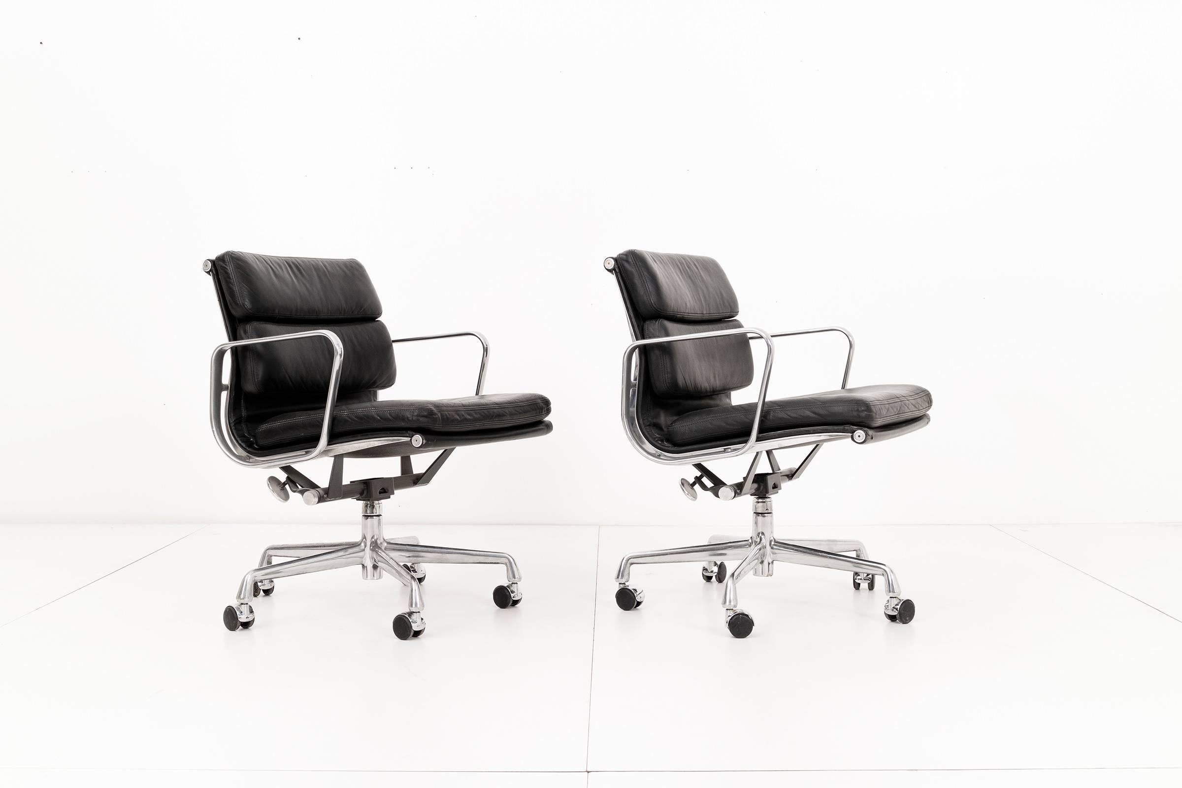 Charles and Ray Eames soft pad collection for Herman Miller. This pair of chairs, styled similarly to the aluminum group, feature plush padded seats and back cushions. The Classic black leather upholstery is in excellent vintage condition. The